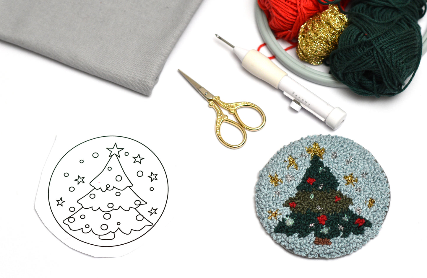 Punch needle coaster craft kit with Christmas tree design, yarn, and tools on a white background