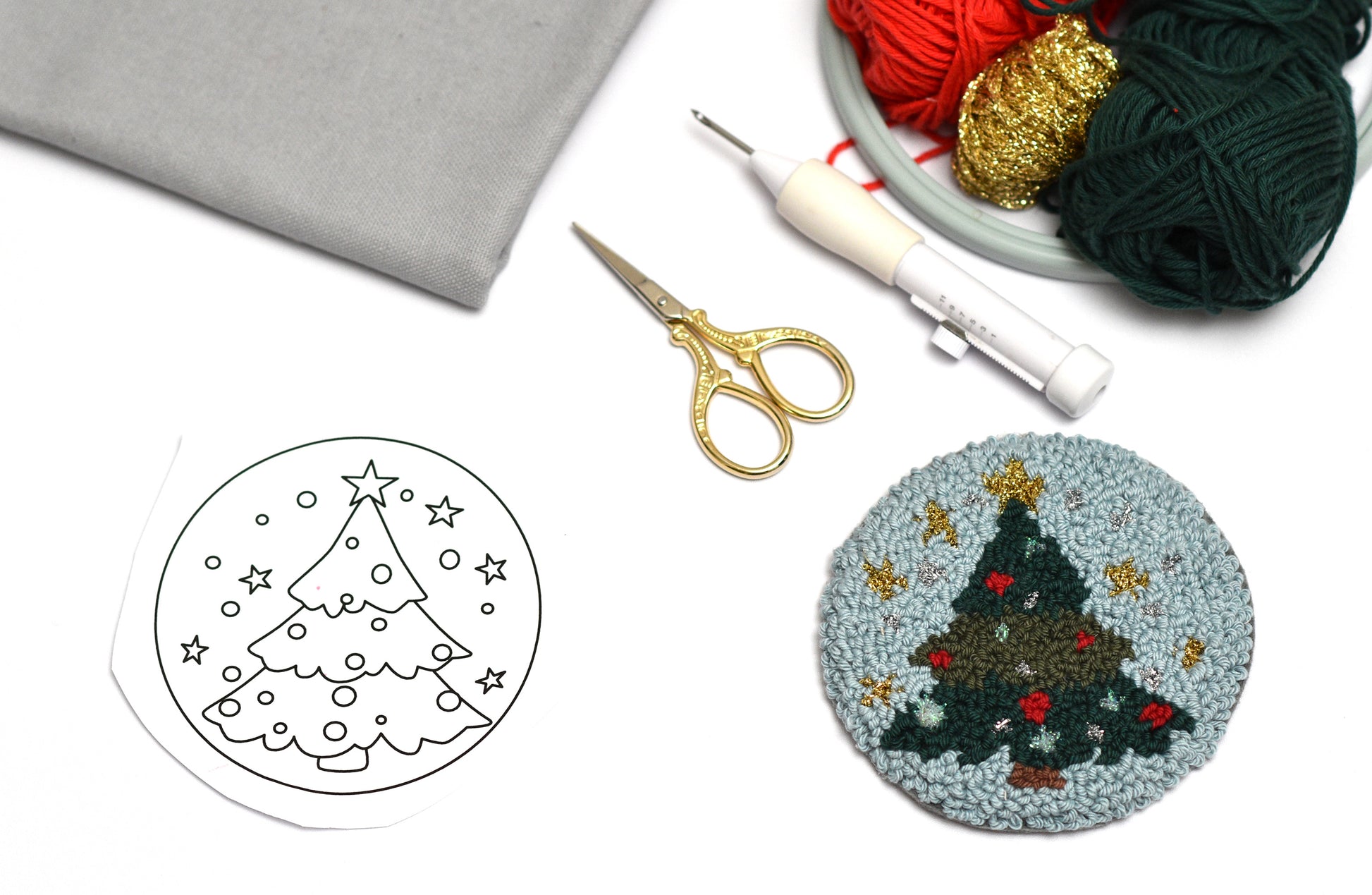 Punch needle coaster craft kit with Christmas tree design, yarn, and tools on a white background