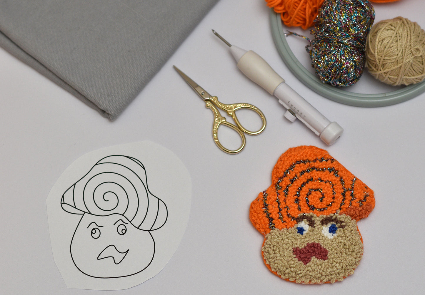 Handmade punch needle coaster with yarn and tools on a table