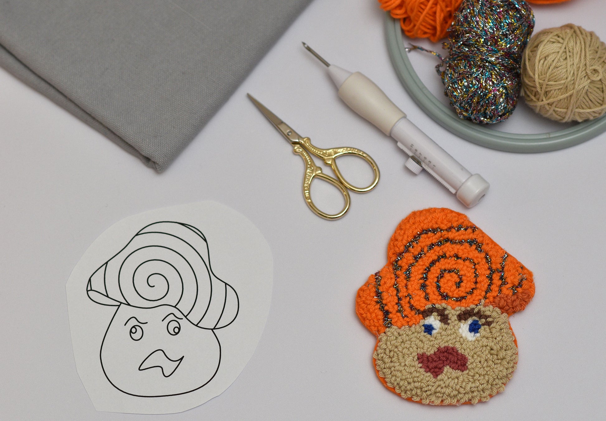 Handmade punch needle coaster with yarn and tools on a table