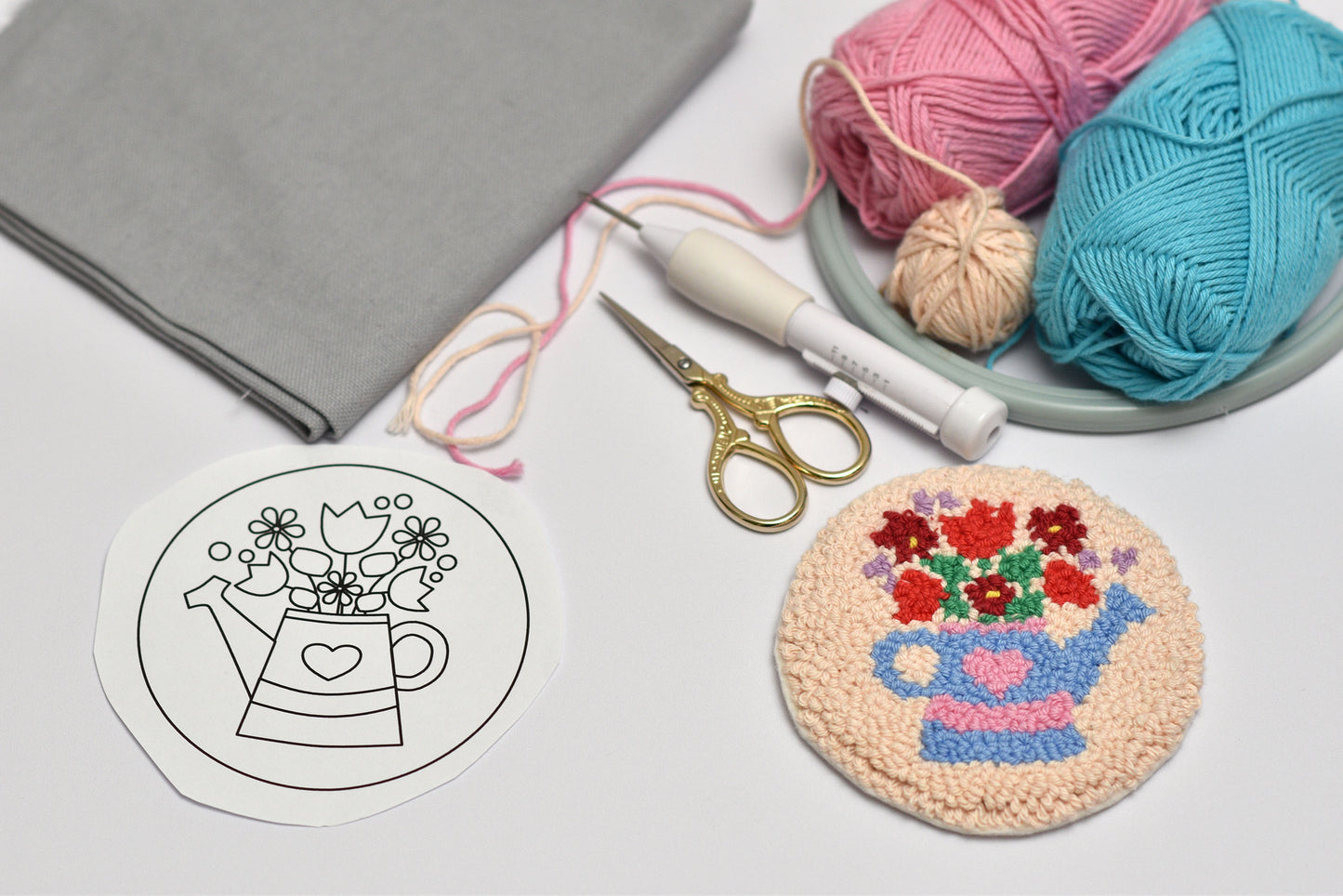 Embroidered coaster with flower design next to yarn and tools on a light surface