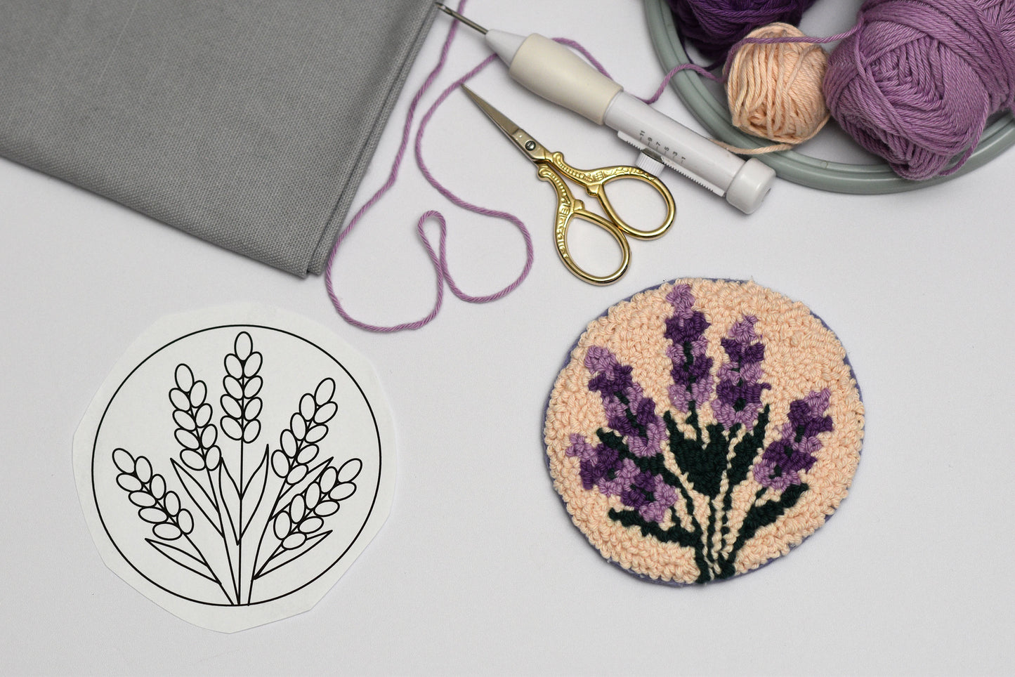 Embroidery hoop with floral lavender design, scissors, and yarn on a table