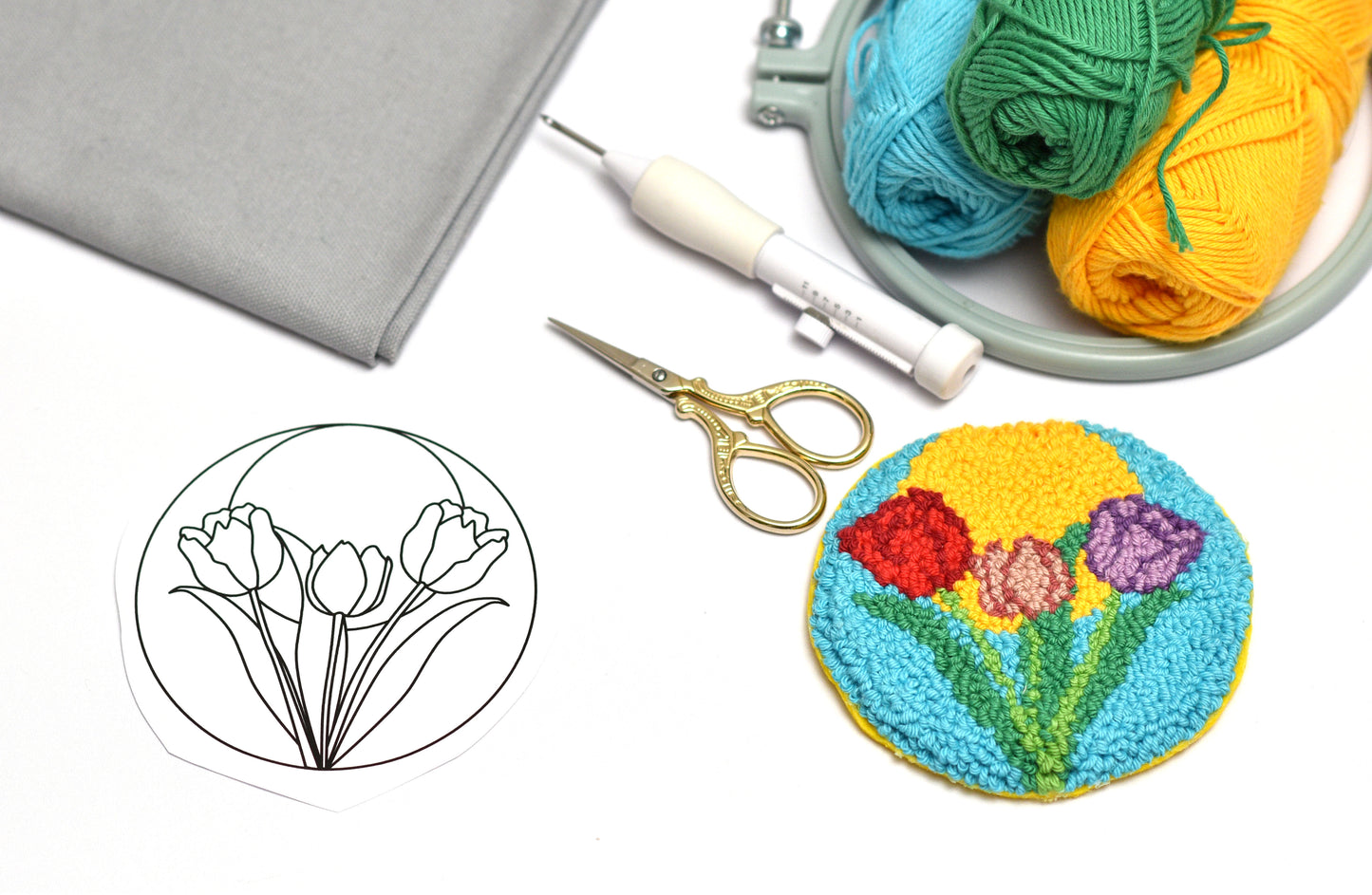 Embroidery hoop with colorful yarn, scissors, and embroidered flower design on a white background.