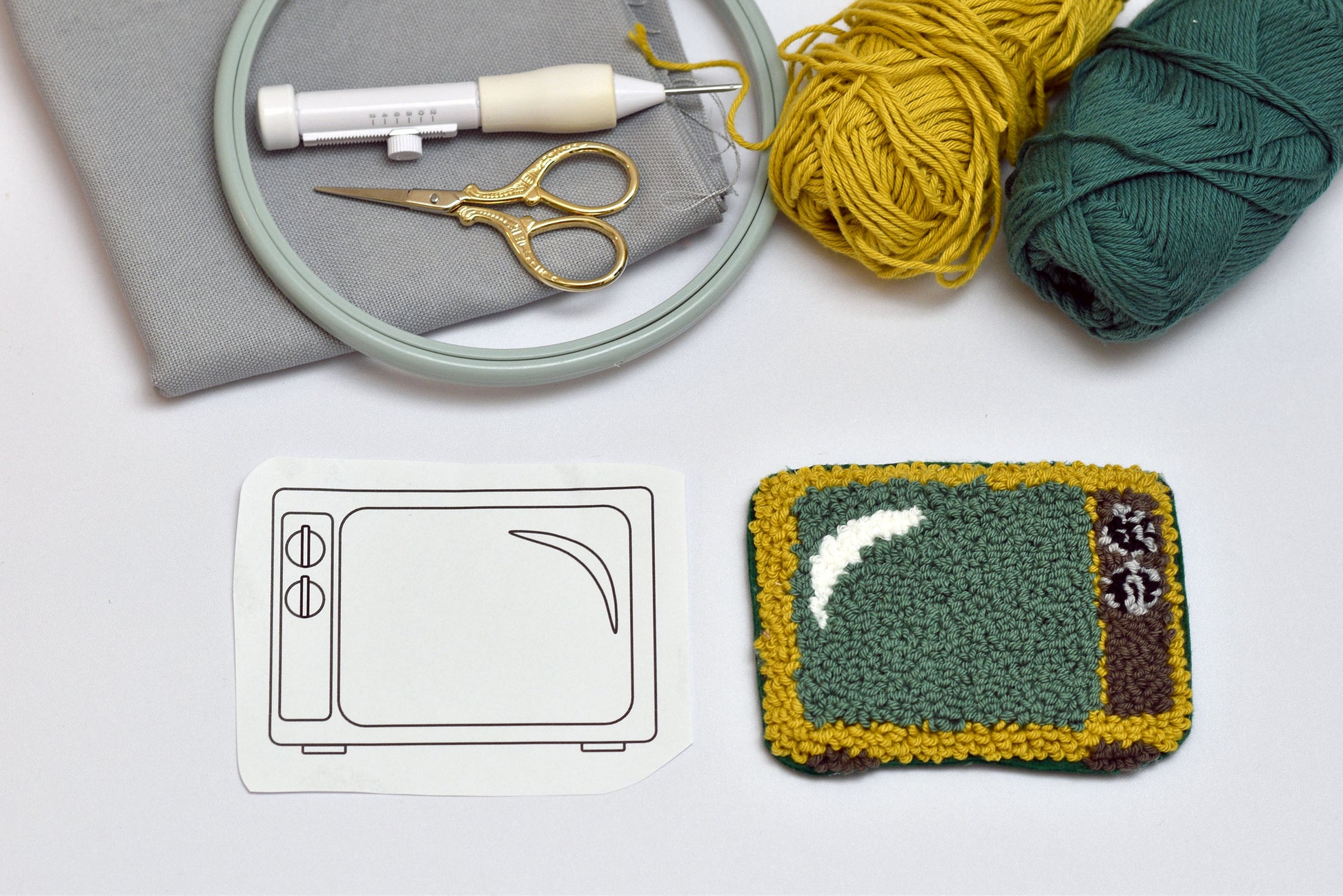 Punch needle coaster of a television screen with yarn, scissors, and embroidery hoop on a light surface.