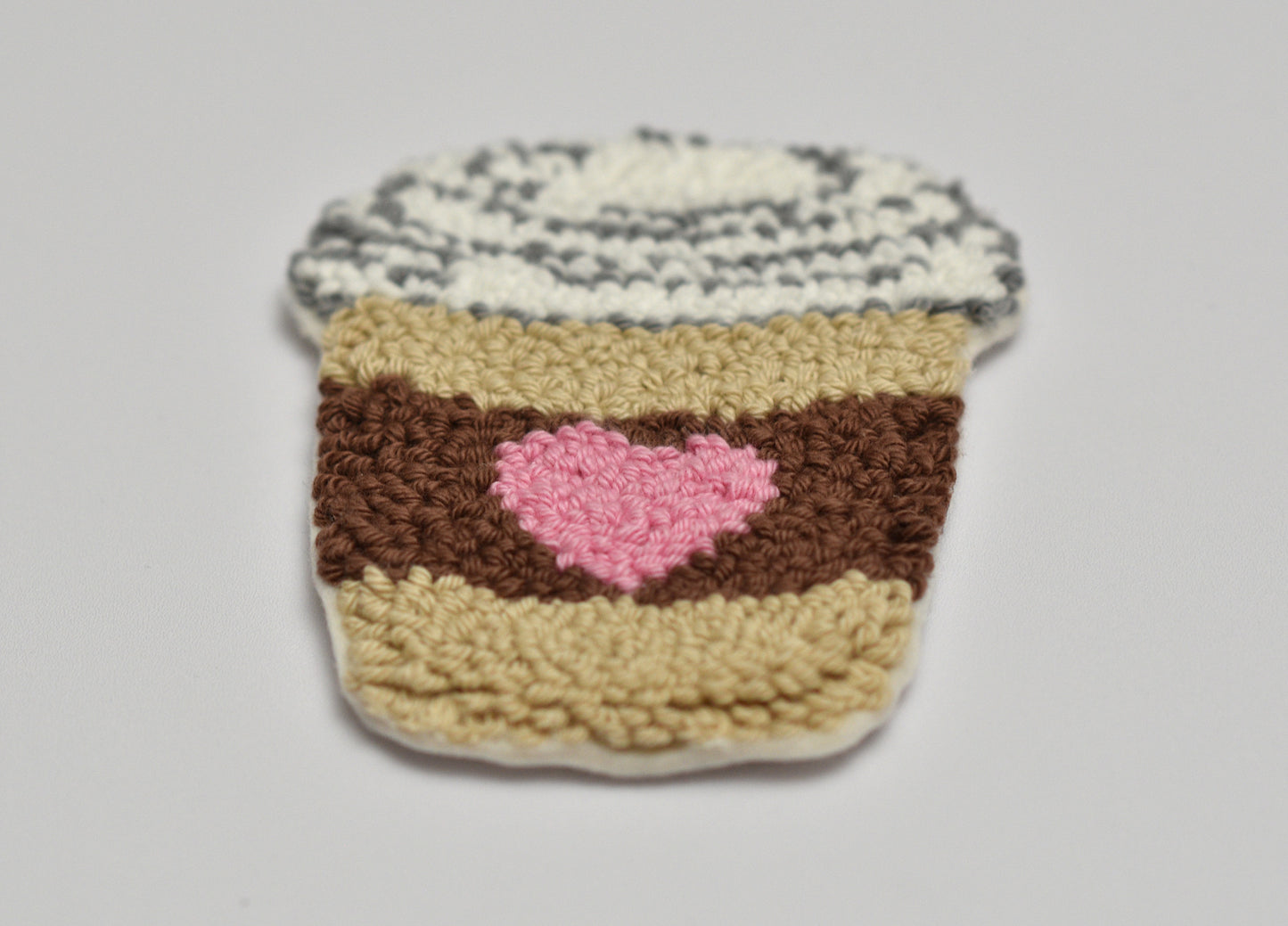 Embroidered Coffee cup coaster with pink heart on a light gray background