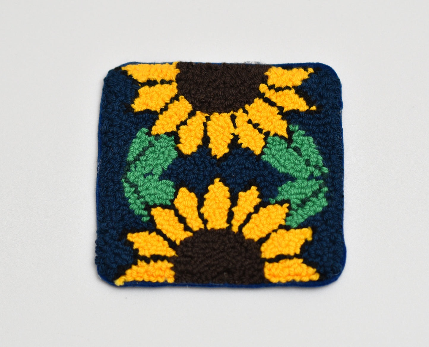 Square woven coaster with sunflower design on a plain background