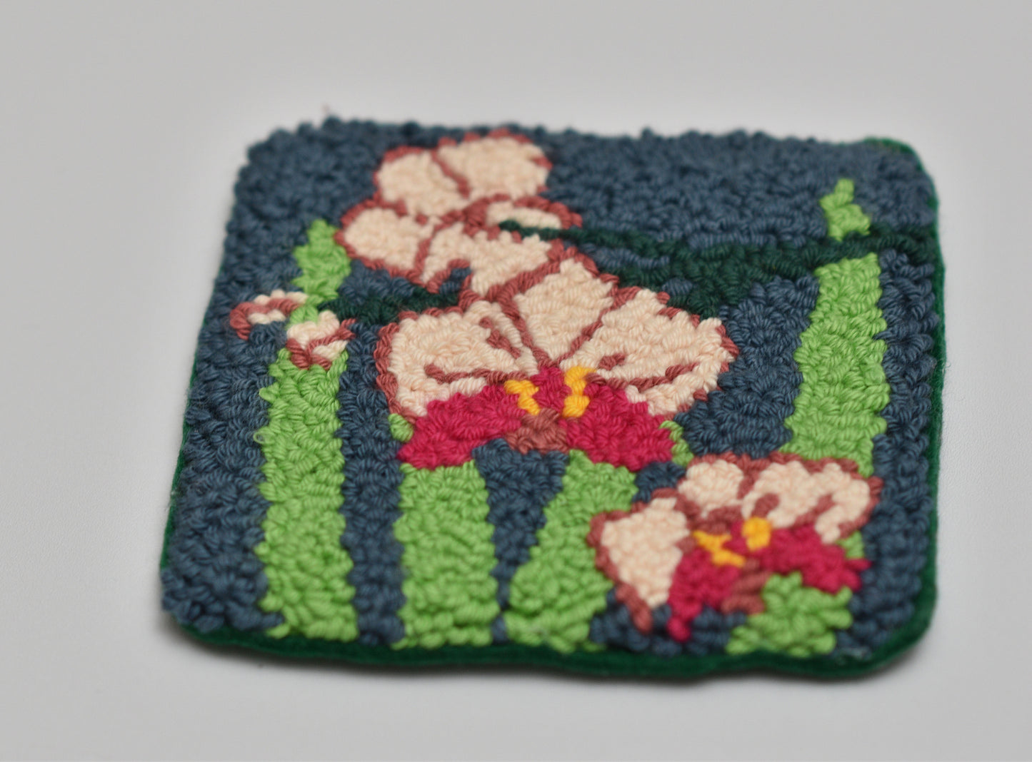 Handmade mug rug with floral orchid design on a plain background