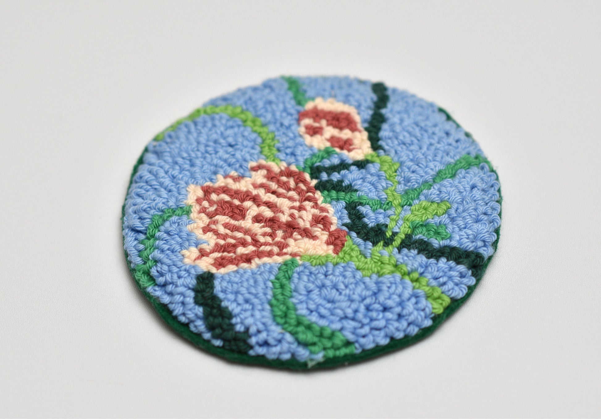 Round mug rug with floral design on a light gray background