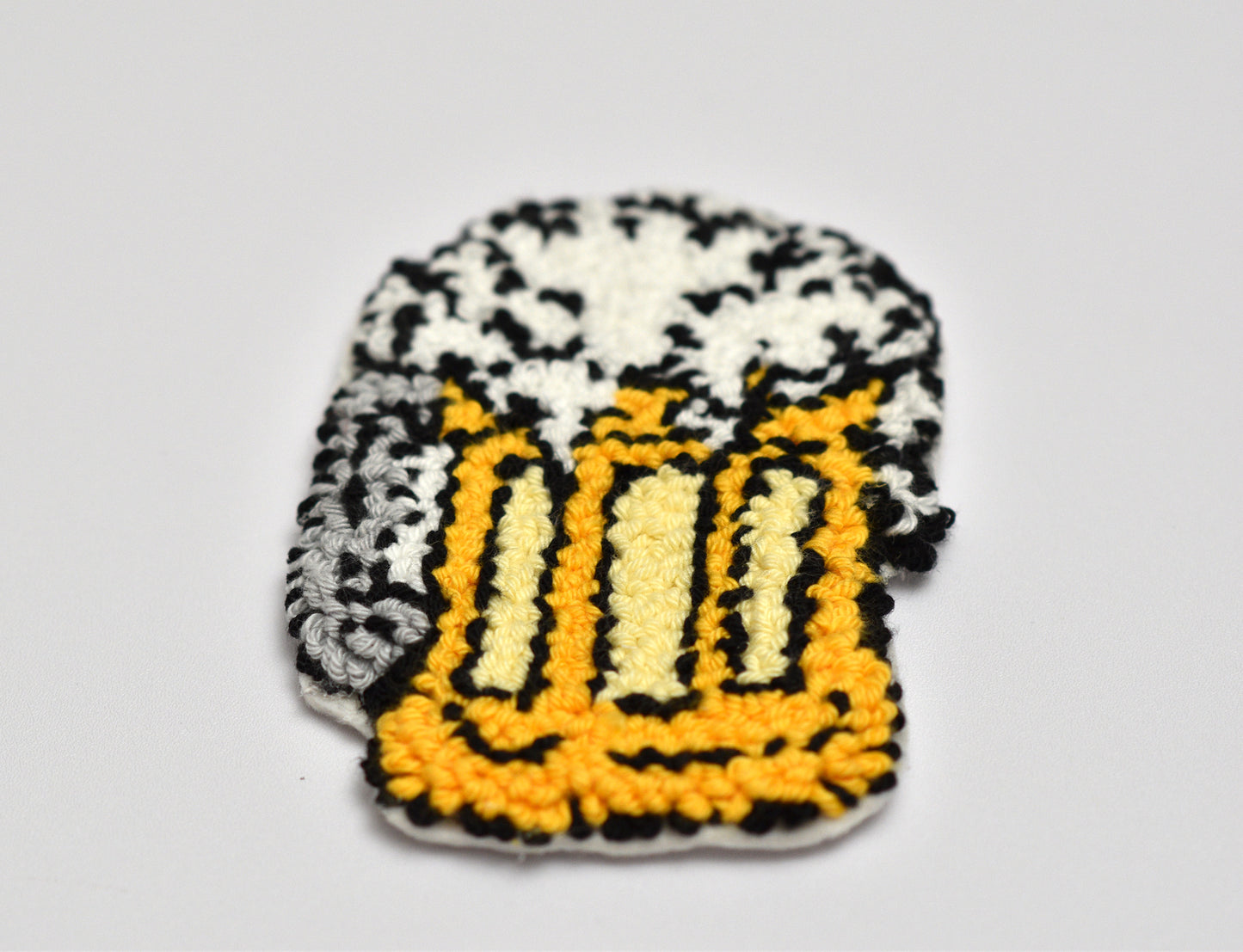 Embroidered coaster with a beer mug design on a gray background