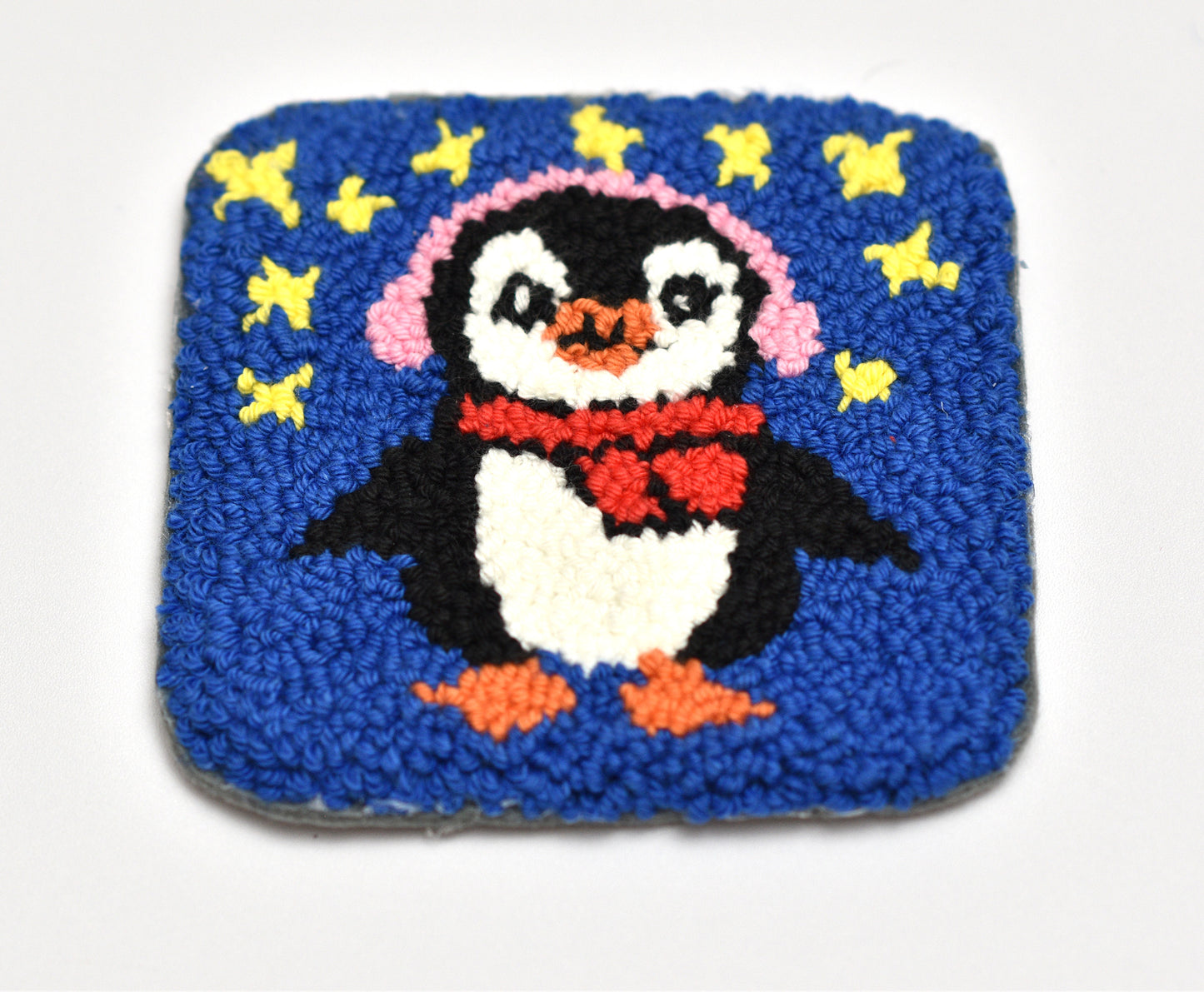 Handmade coaster with a penguin design on a blue background