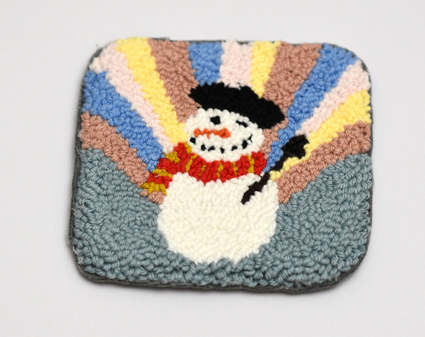Colorful mug rug with a snowman design on a plain background