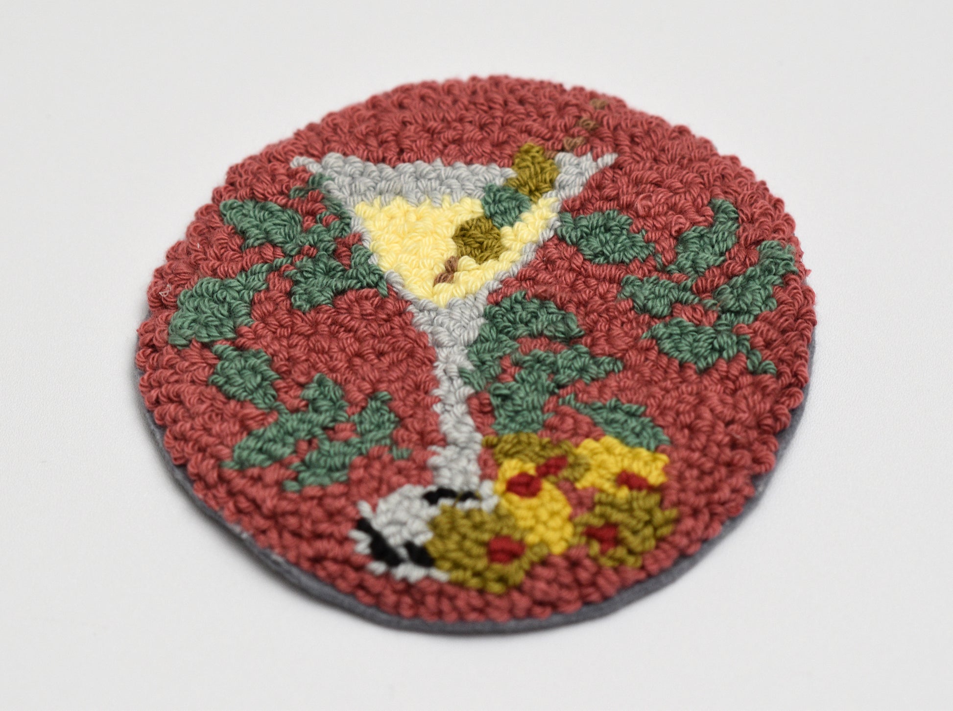 Round woven coaster with a martini glass design on a white background