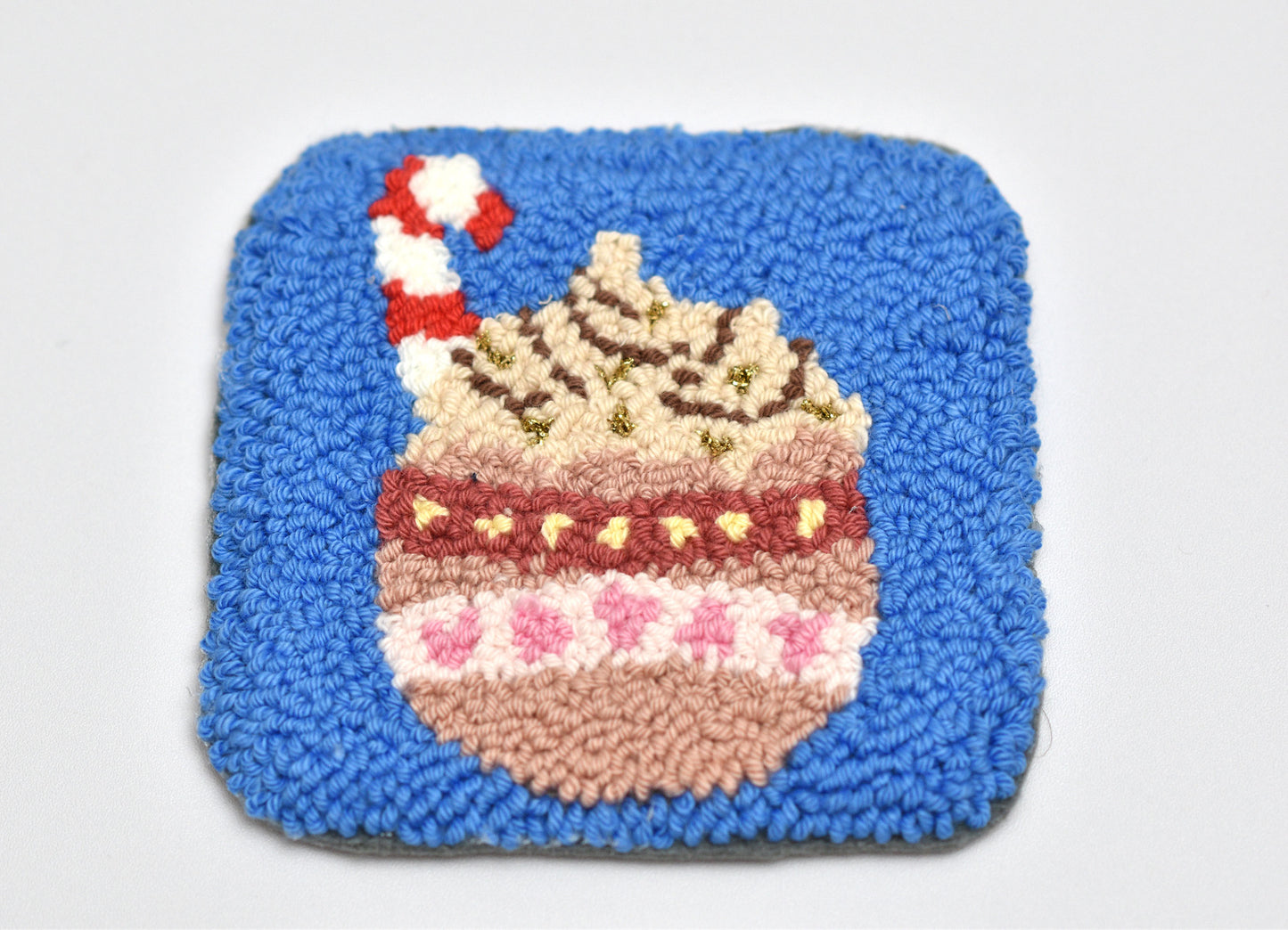 Square punch needle coaster with a hot cocoa mug design on a white background