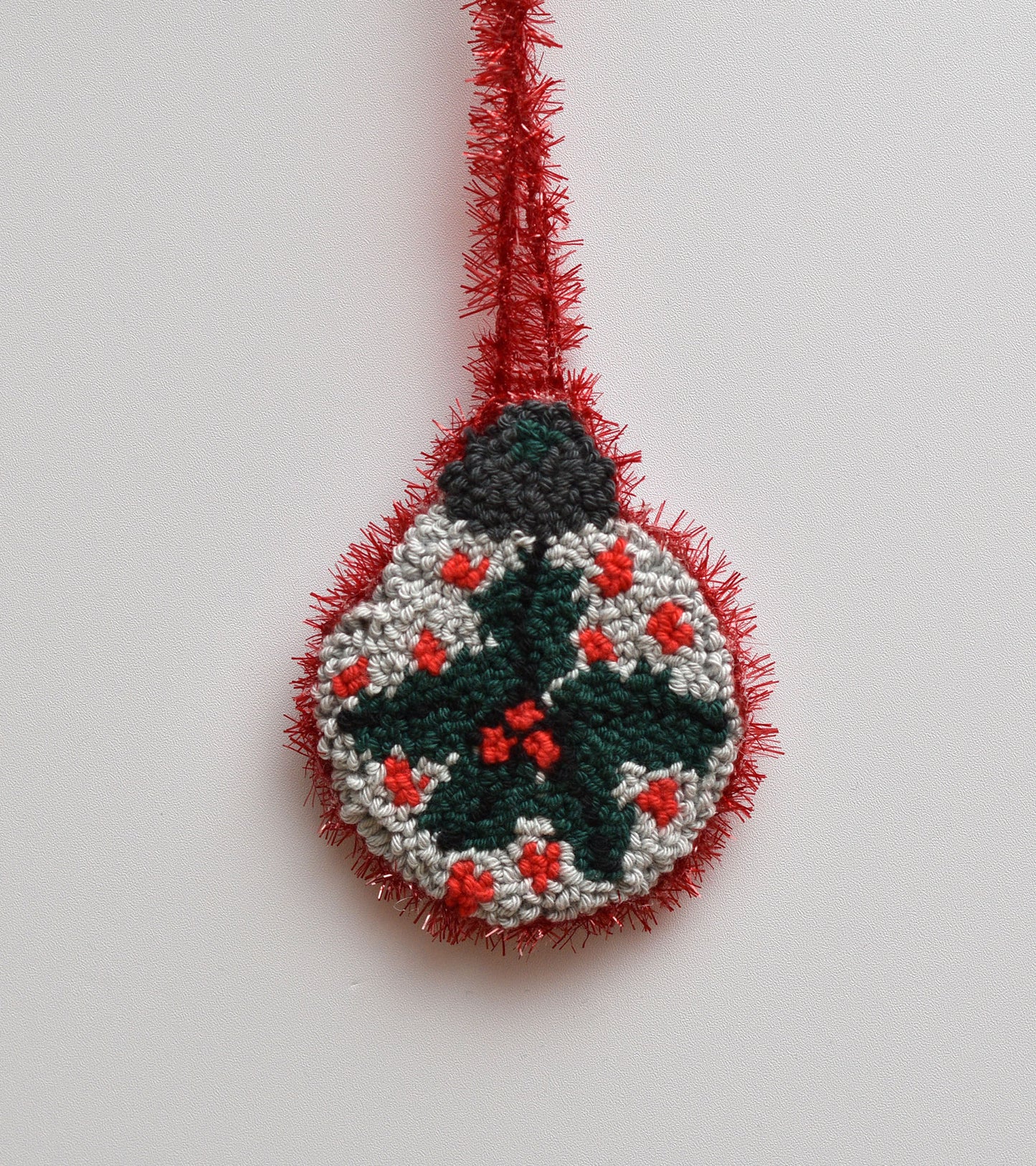 Decorative punch needled ornament with mistletoe design on a plain background
