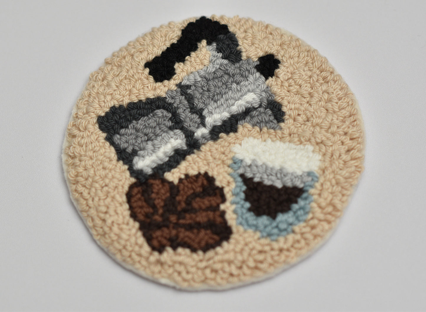 Round punch needle mug rug with Espresso coffee-themed design on a plain background