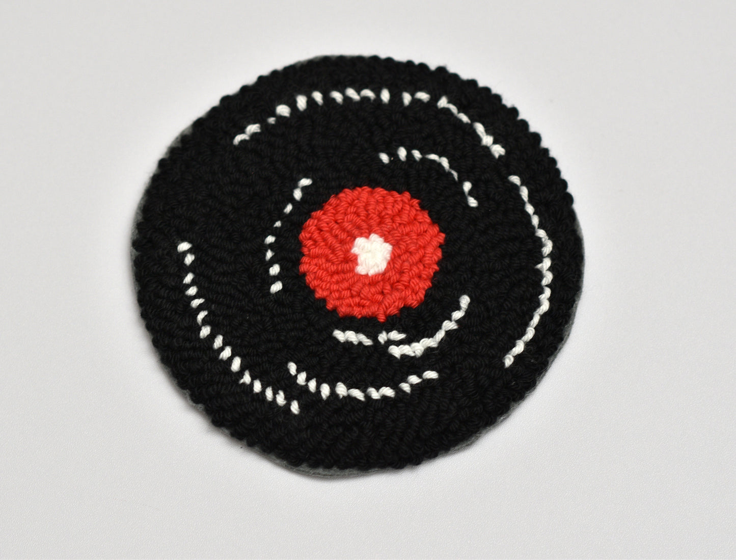 Punch needle Vinyl designed coaster with concentric circles on a gray background