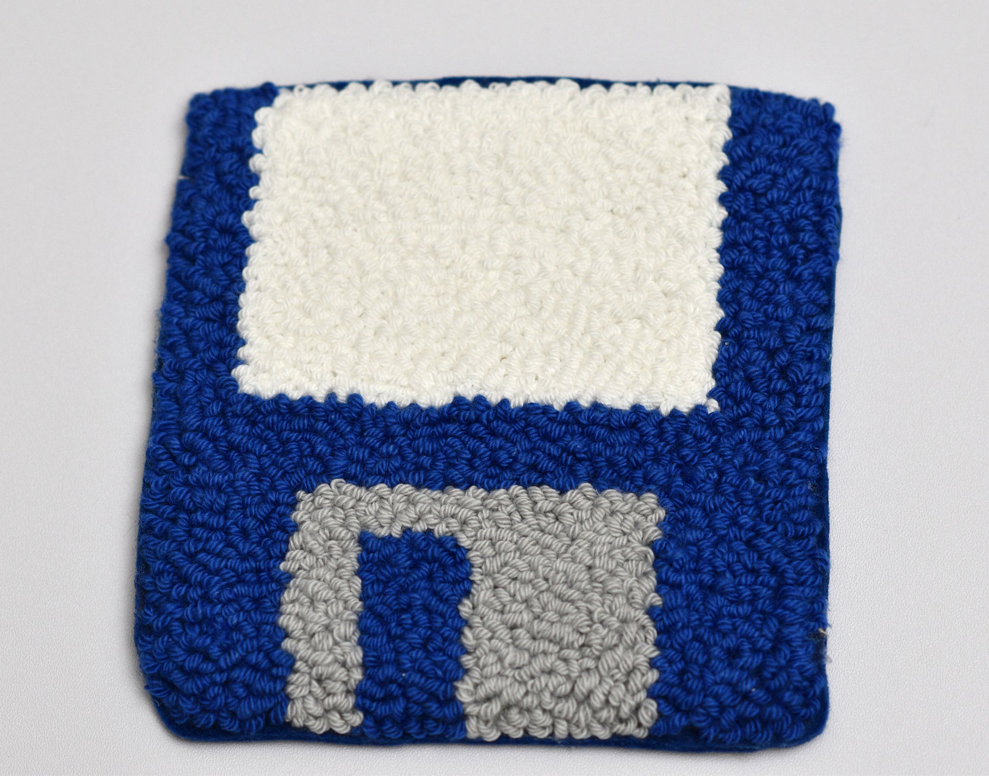 Punch needled square coaster with a floppy disk design on a white background