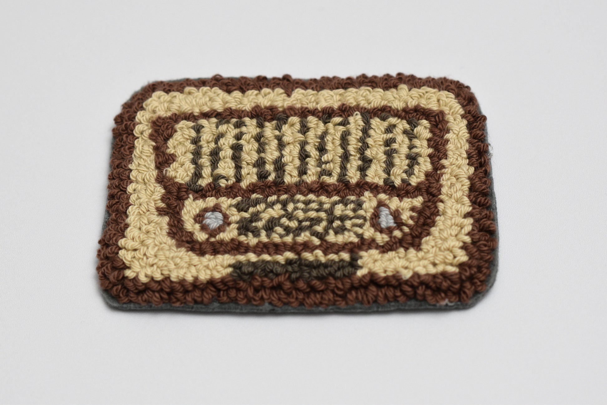 Punch needle coaster with a retro radio design on a plain background