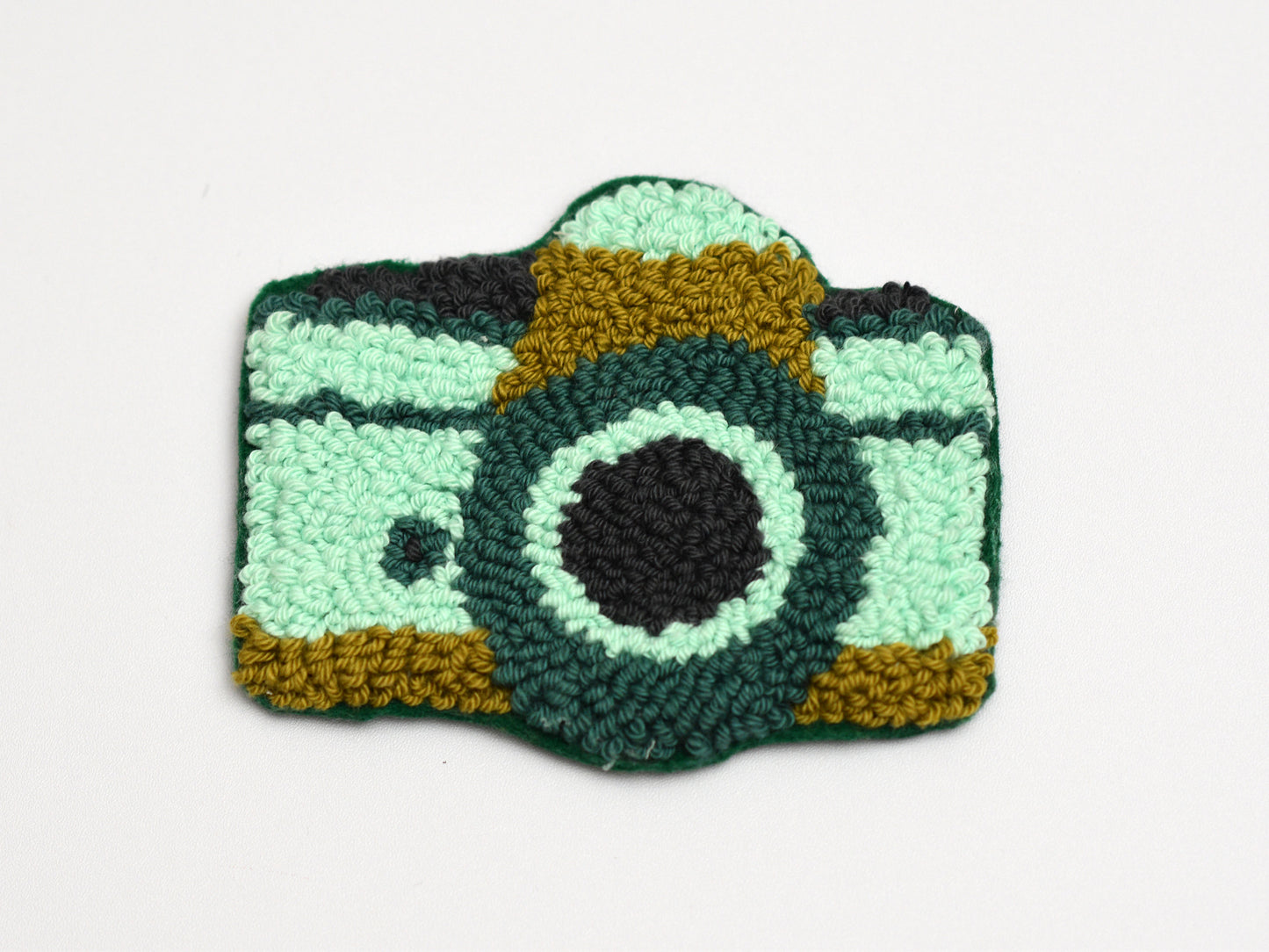 Embroidered camera-shaped coaster on a white background