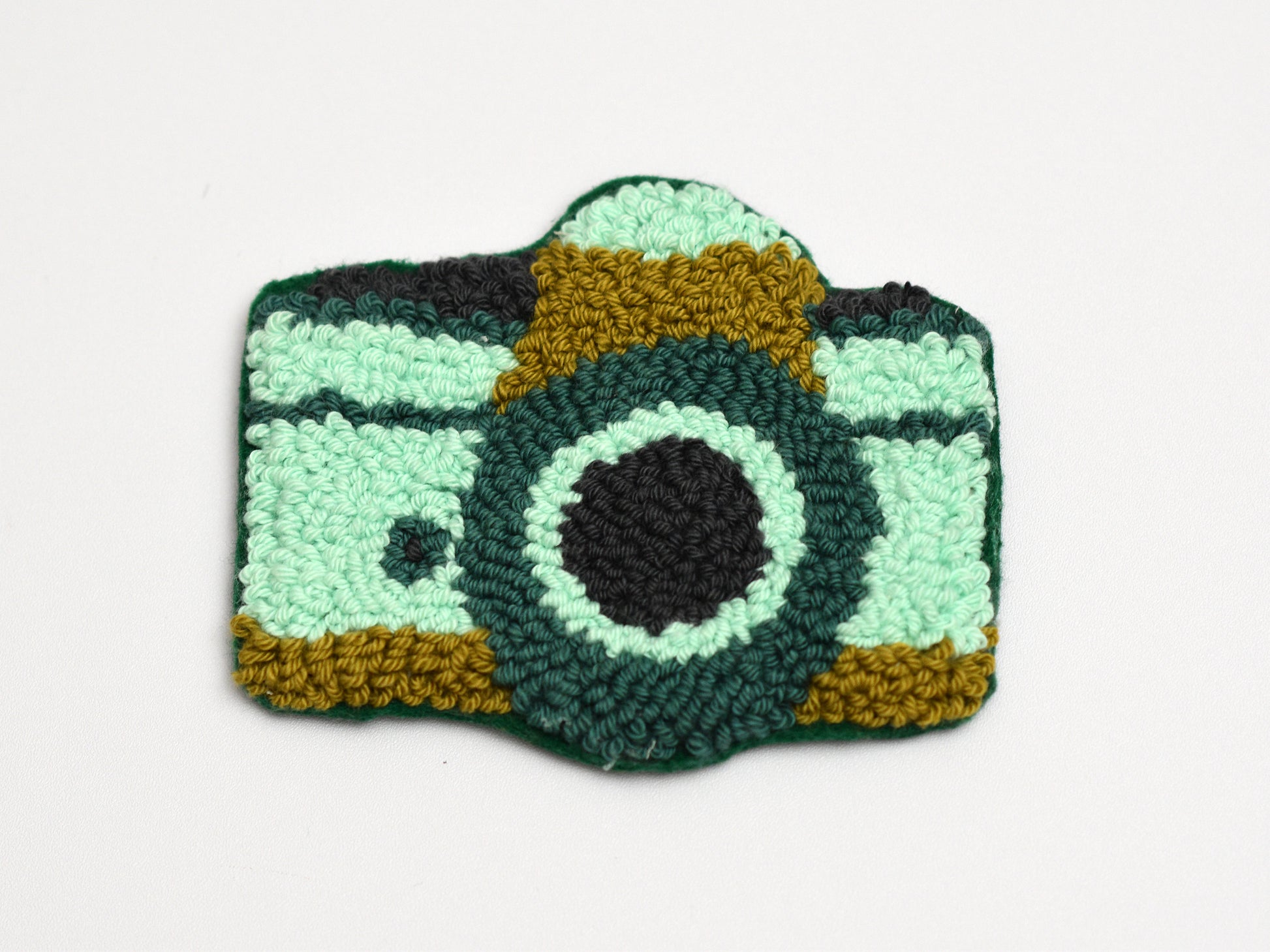 Embroidered camera-shaped coaster on a white background