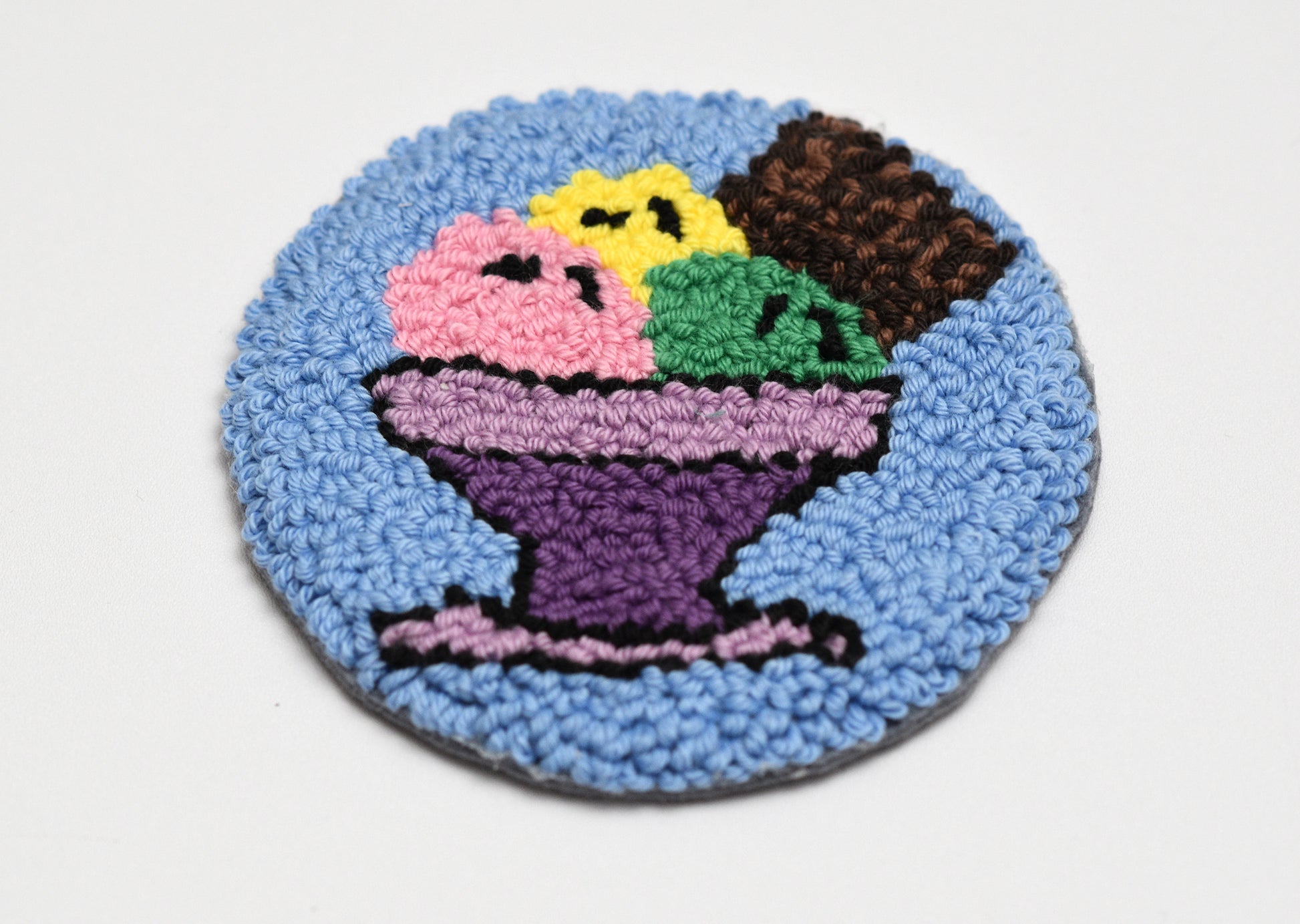 Round embroidered coaster with ice cream design on a white background