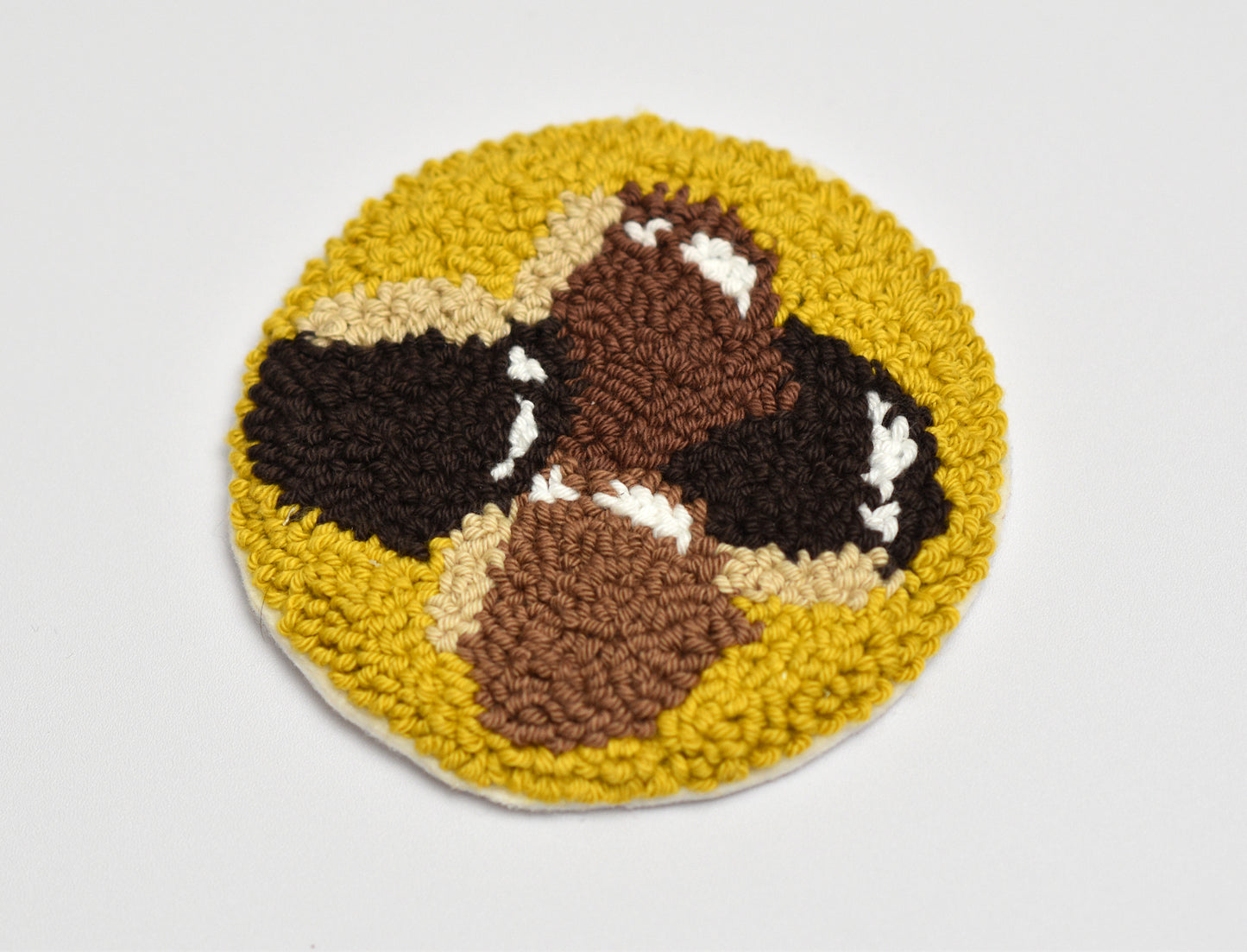 Round punch needle mug rug with chestnuts design on a white background
