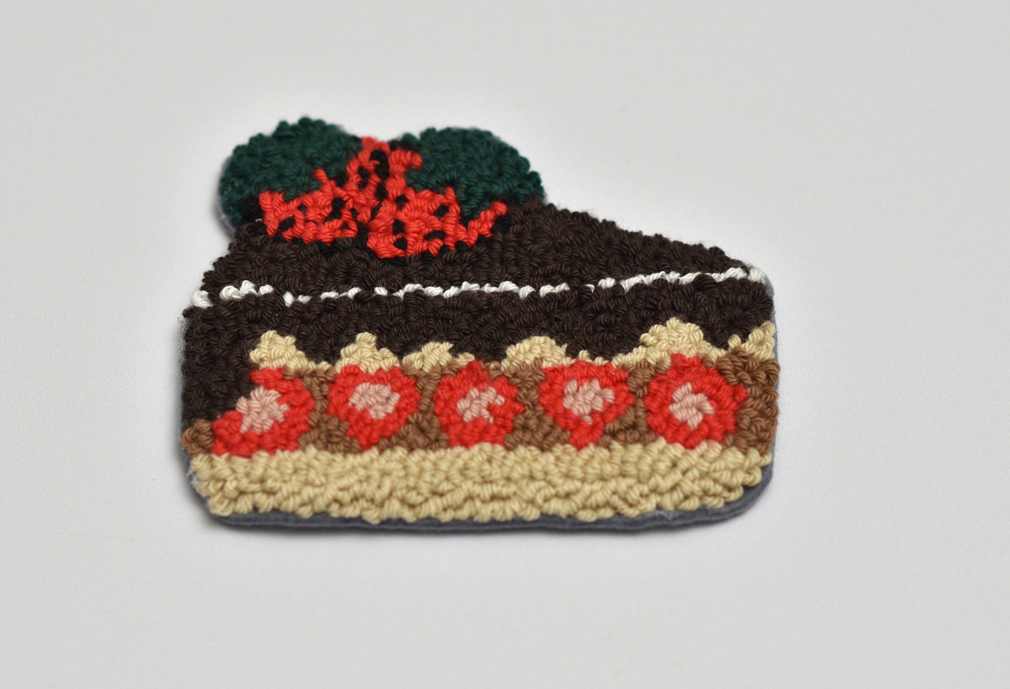 Punch needled cake-shaped coaster with a white background