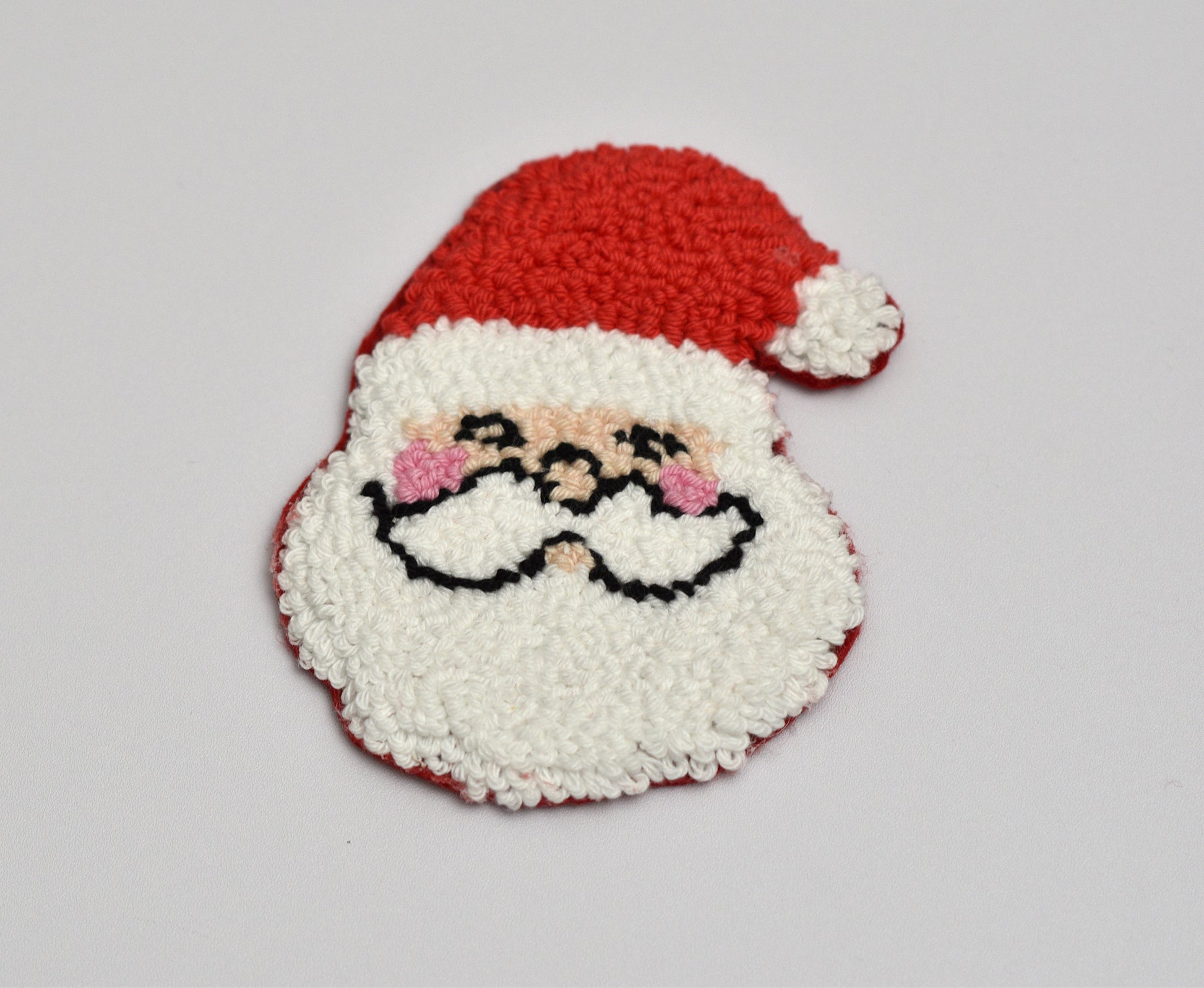 Punch needle Coaster with Santa Claus design on a light gray background
