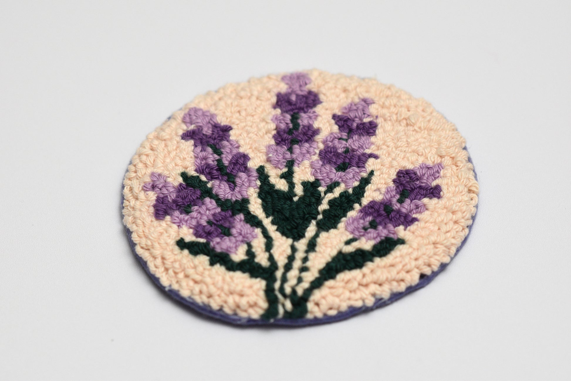 Round woven mug rug with purple lavender design on a light gray background