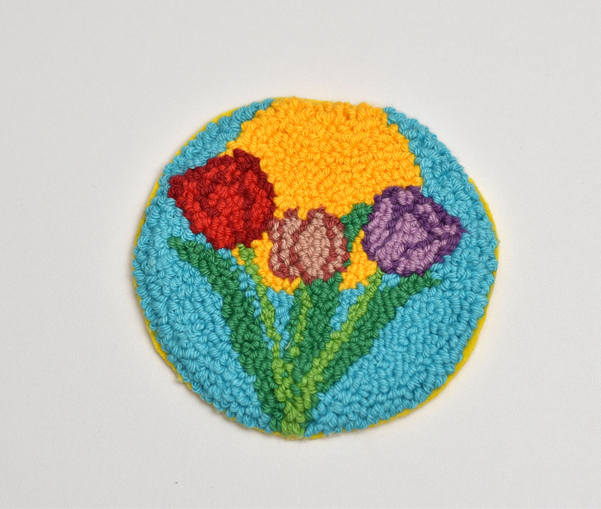 Round embroidered coaster with colorful tulip flowers on a white background