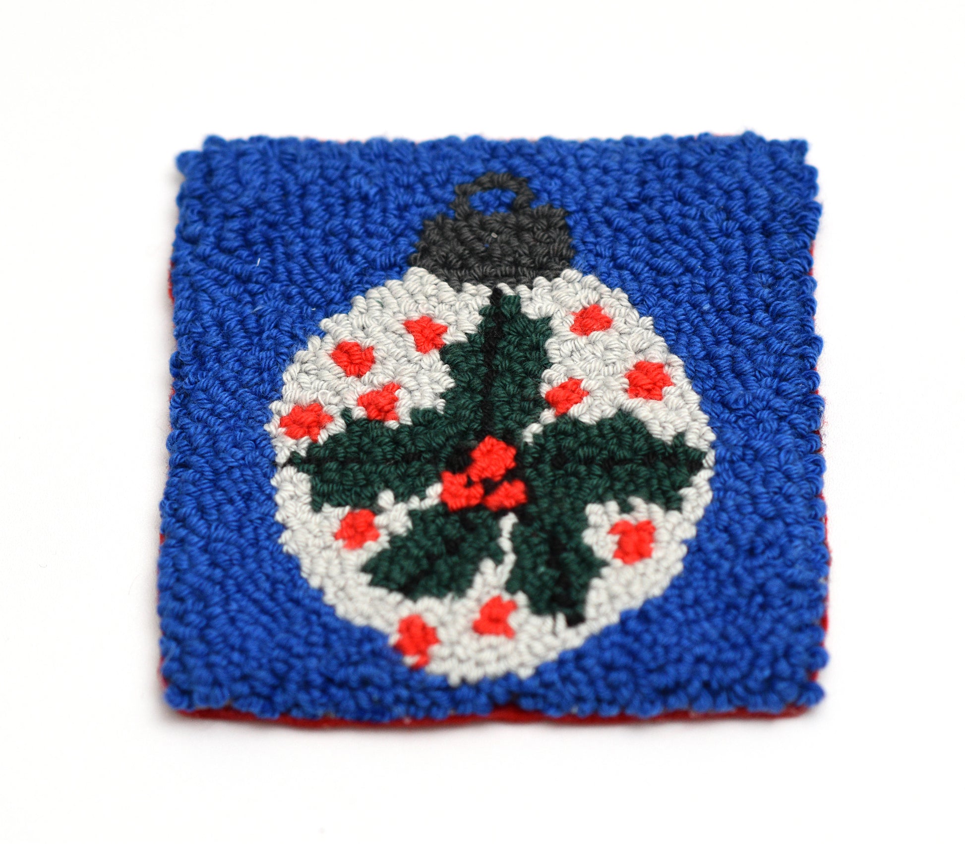 Square punch needled coaster with a Christmas mistletoe design on a blue background