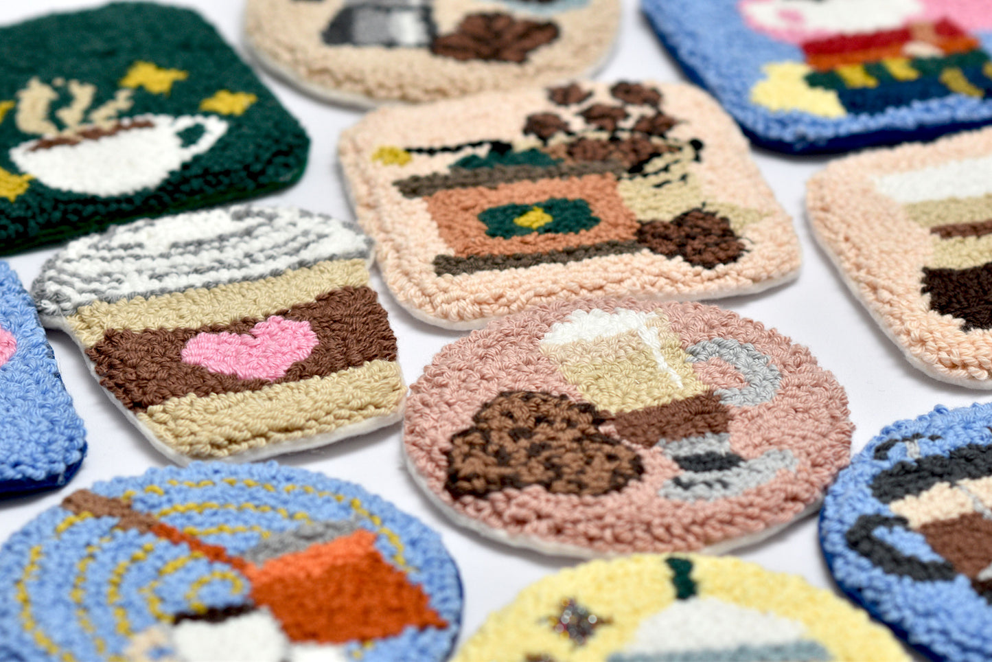 Collection of knitted coffee coasters with various designs on a white background