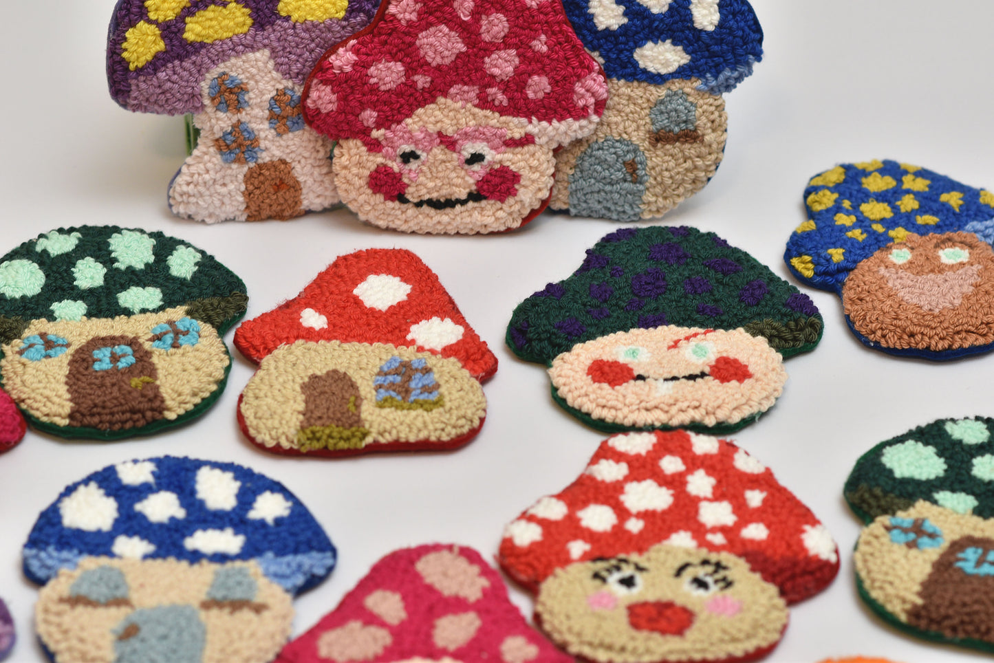 Collection of colorful mushroom-shaped coasters with mushroom faces on a white background