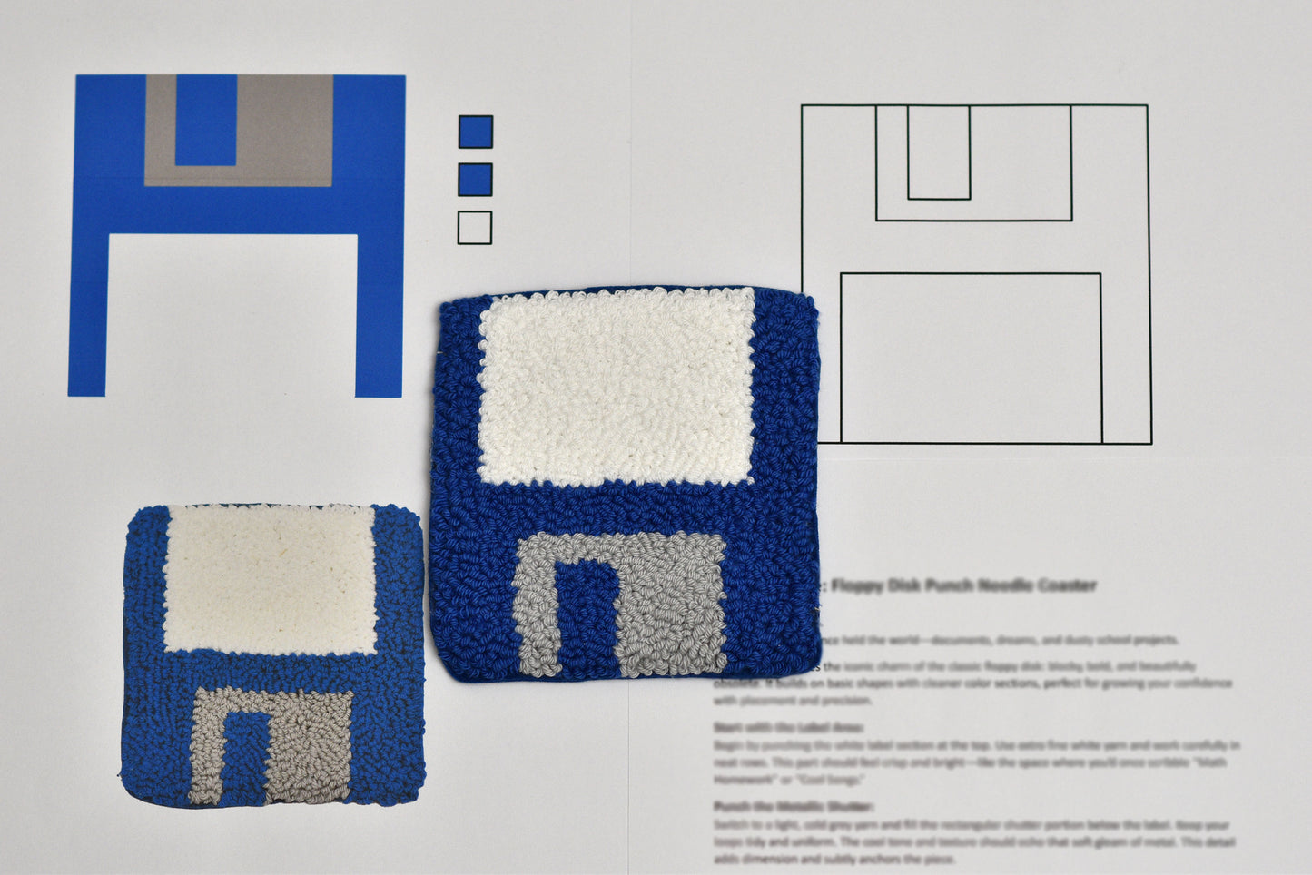 Floppy disk-shaped punch needle coaster with blue and white design on a gray background