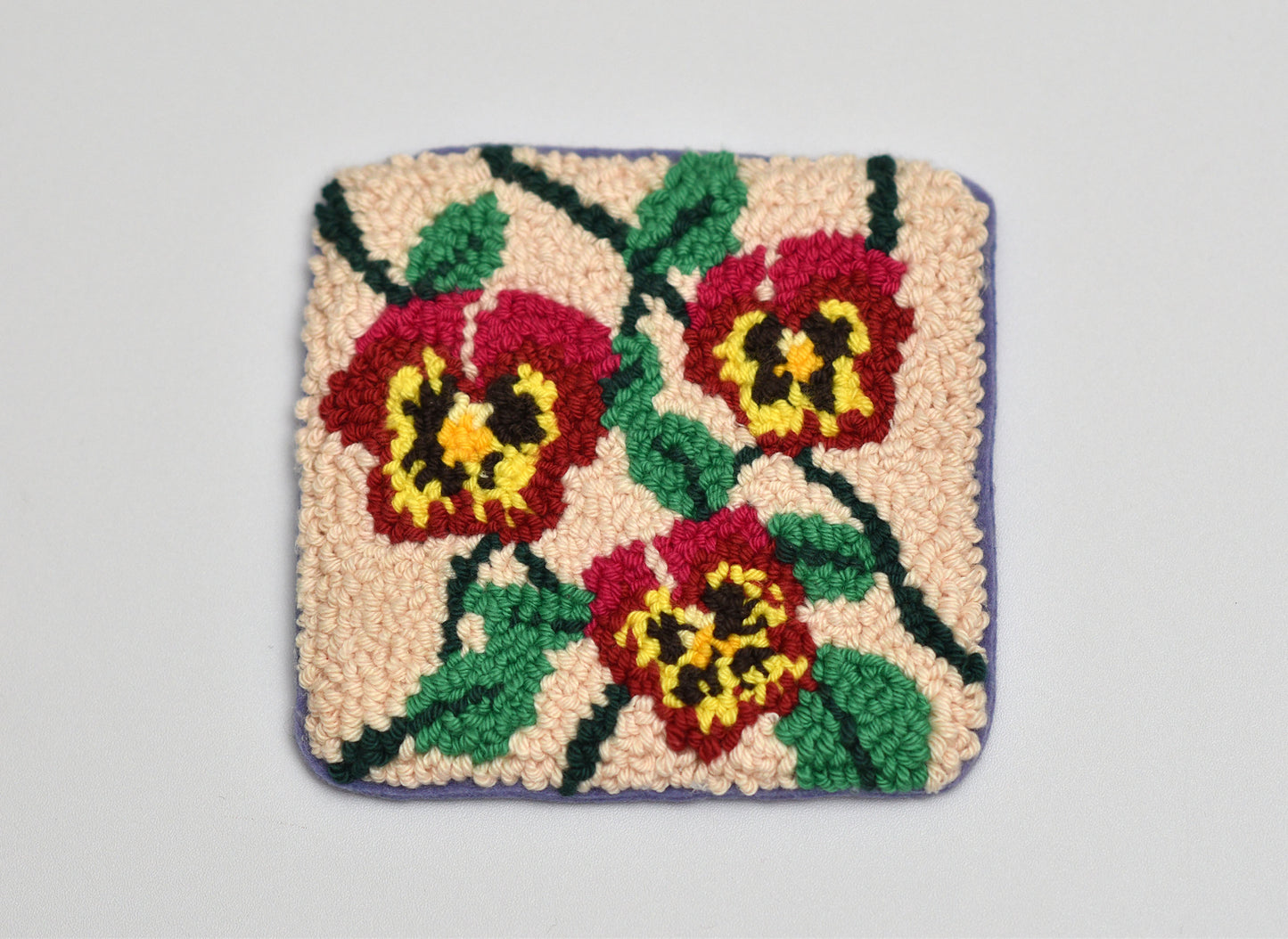 Square coaster with floral pattern on a plain background