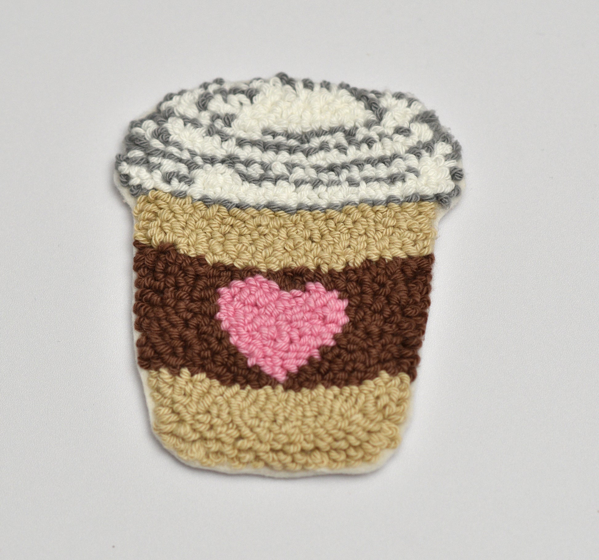 Punch needled coffee cup coaster with a pink heart on a gray background