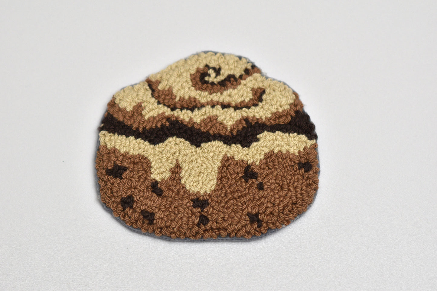 Punch needle coaster resembling a cinnamon roll on a white background