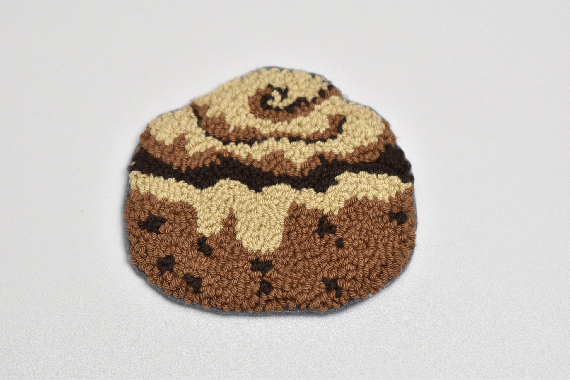 Punch needle coaster resembling a cinnamon roll on a white background