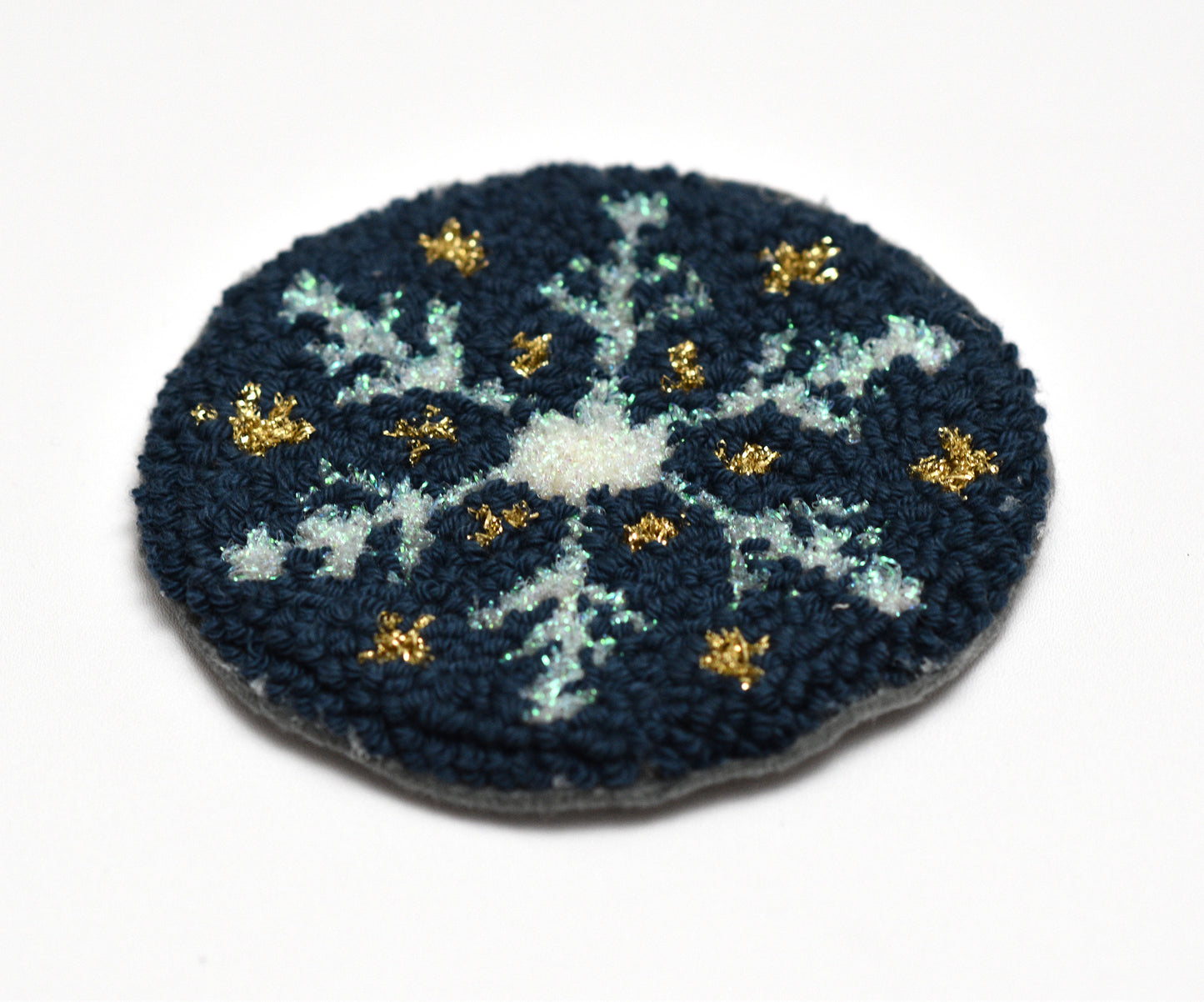 Circular embroidered coaster with a blue and white floral pattern on a white background