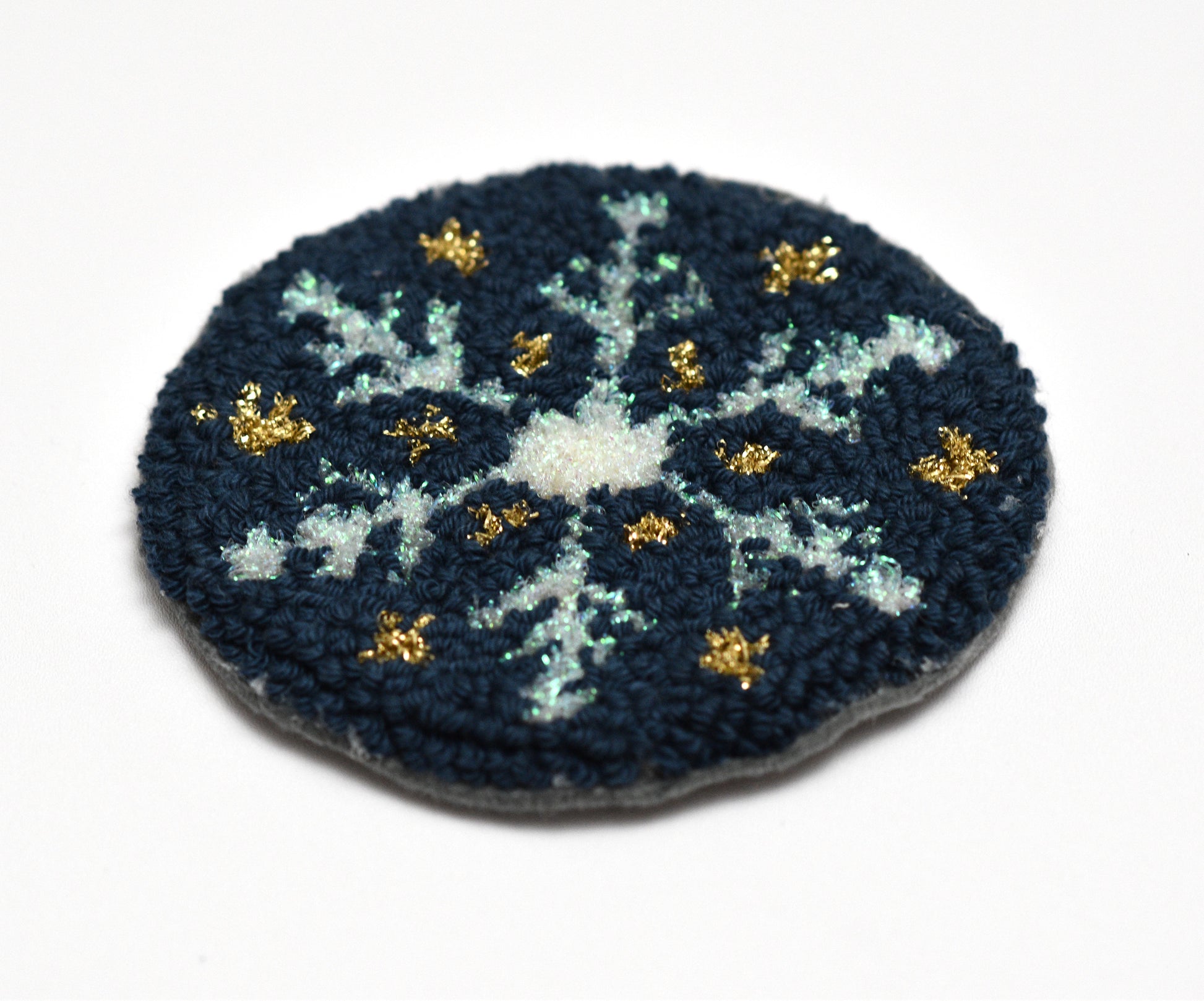 Circular embroidered coaster with a blue and white floral pattern on a white background