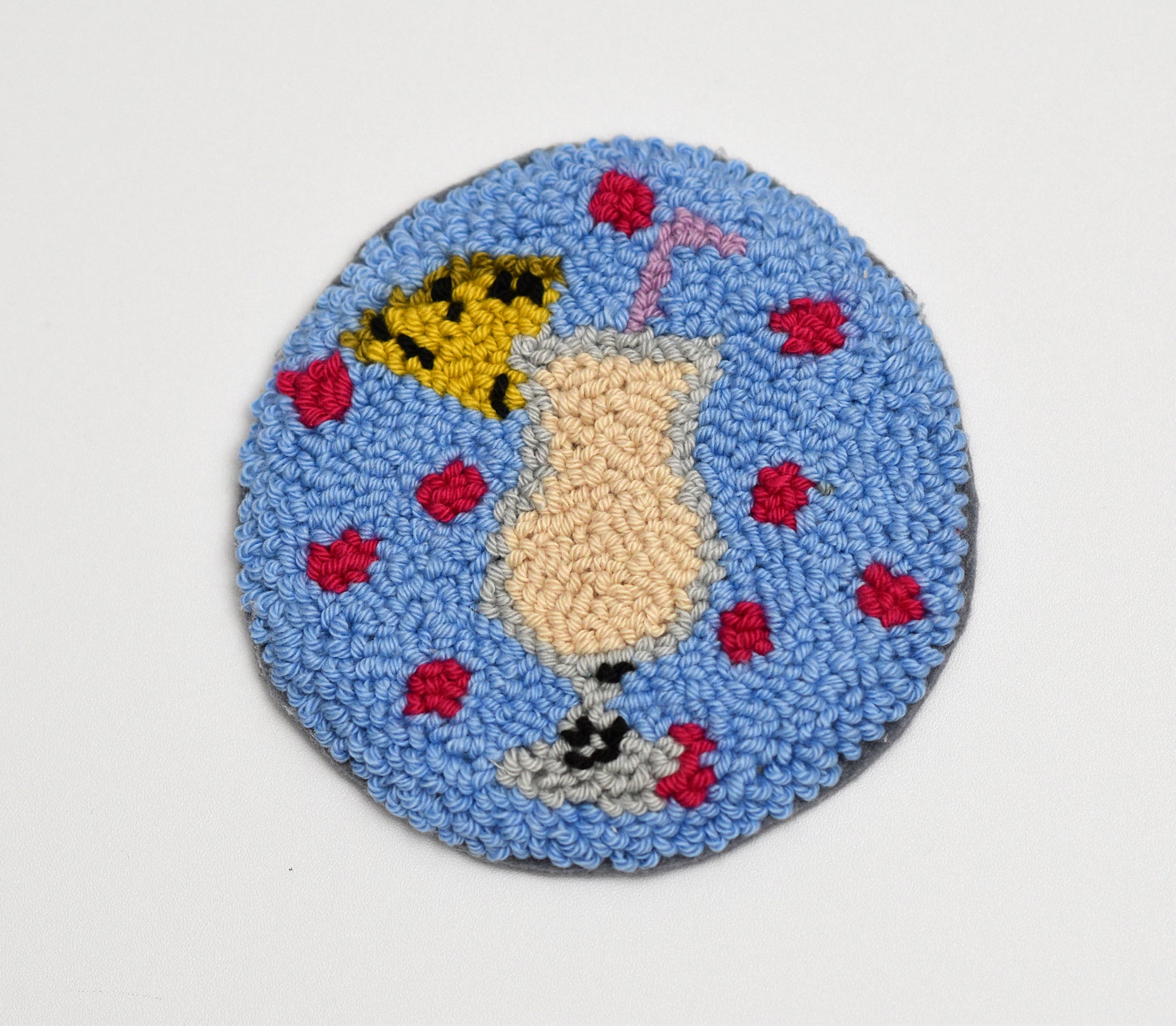 Round blue mug rug with a central design of a glass of Piña Colada on a white background.
