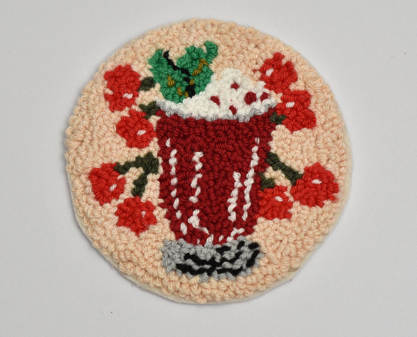 Decorative embroidered mug rug with a cherry cocktail design on a beige background