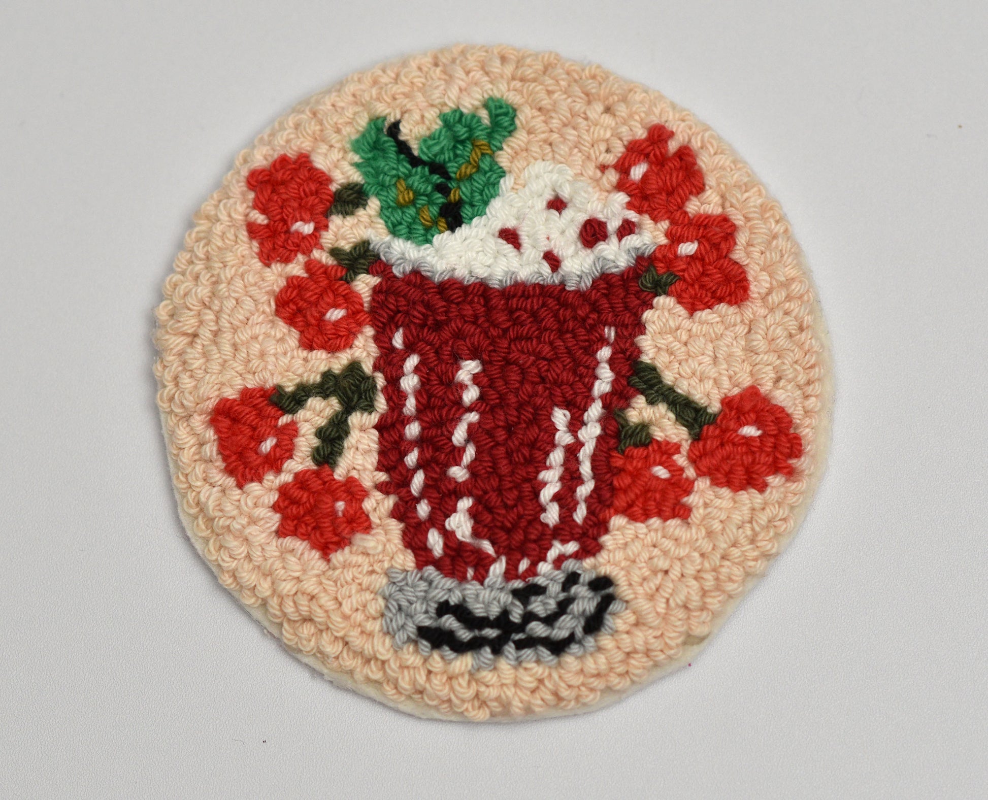 Decorative embroidered mug rug with a cherry cocktail design on a beige background
