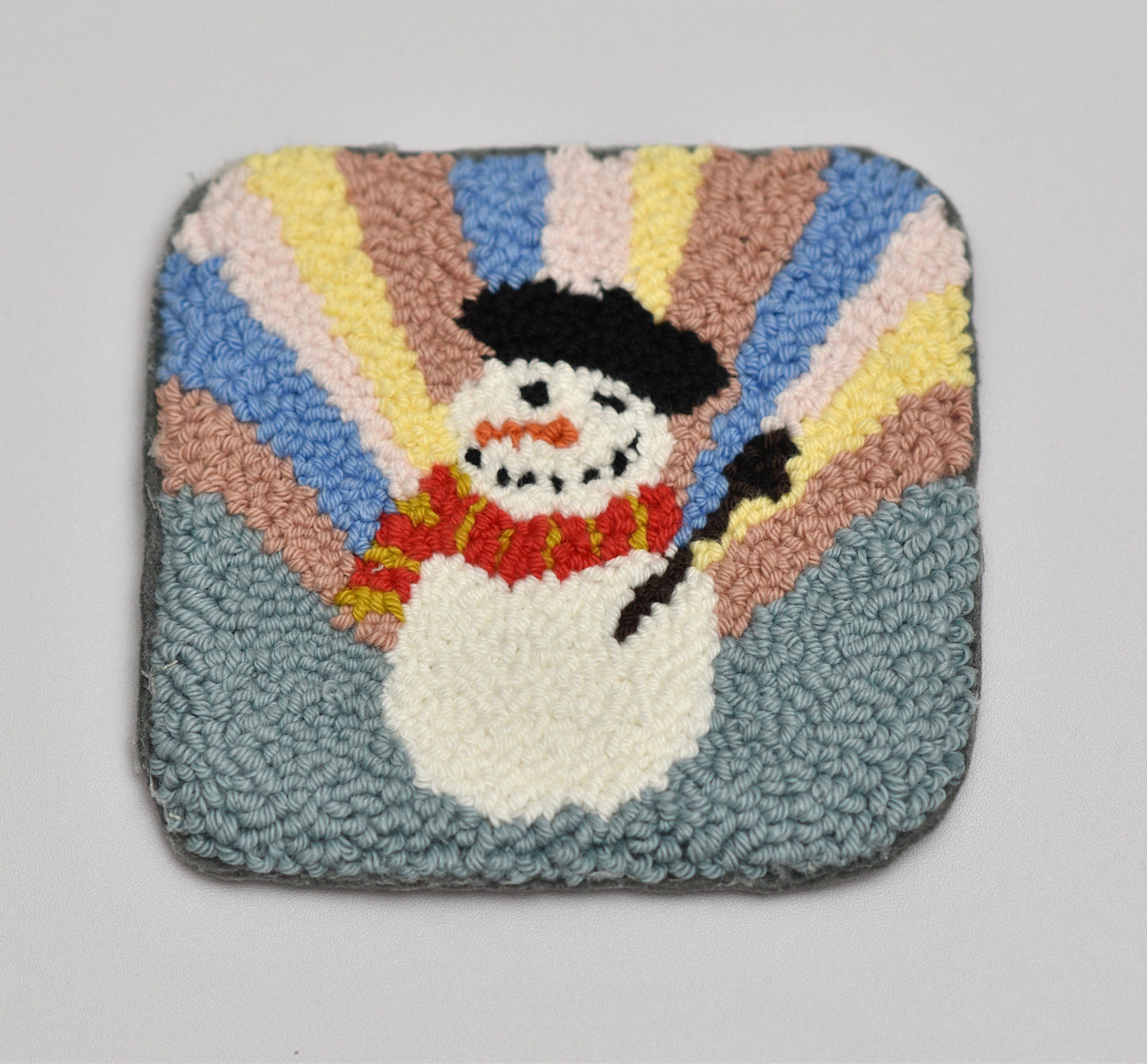 Square mug rug with a snowman design on a plain background