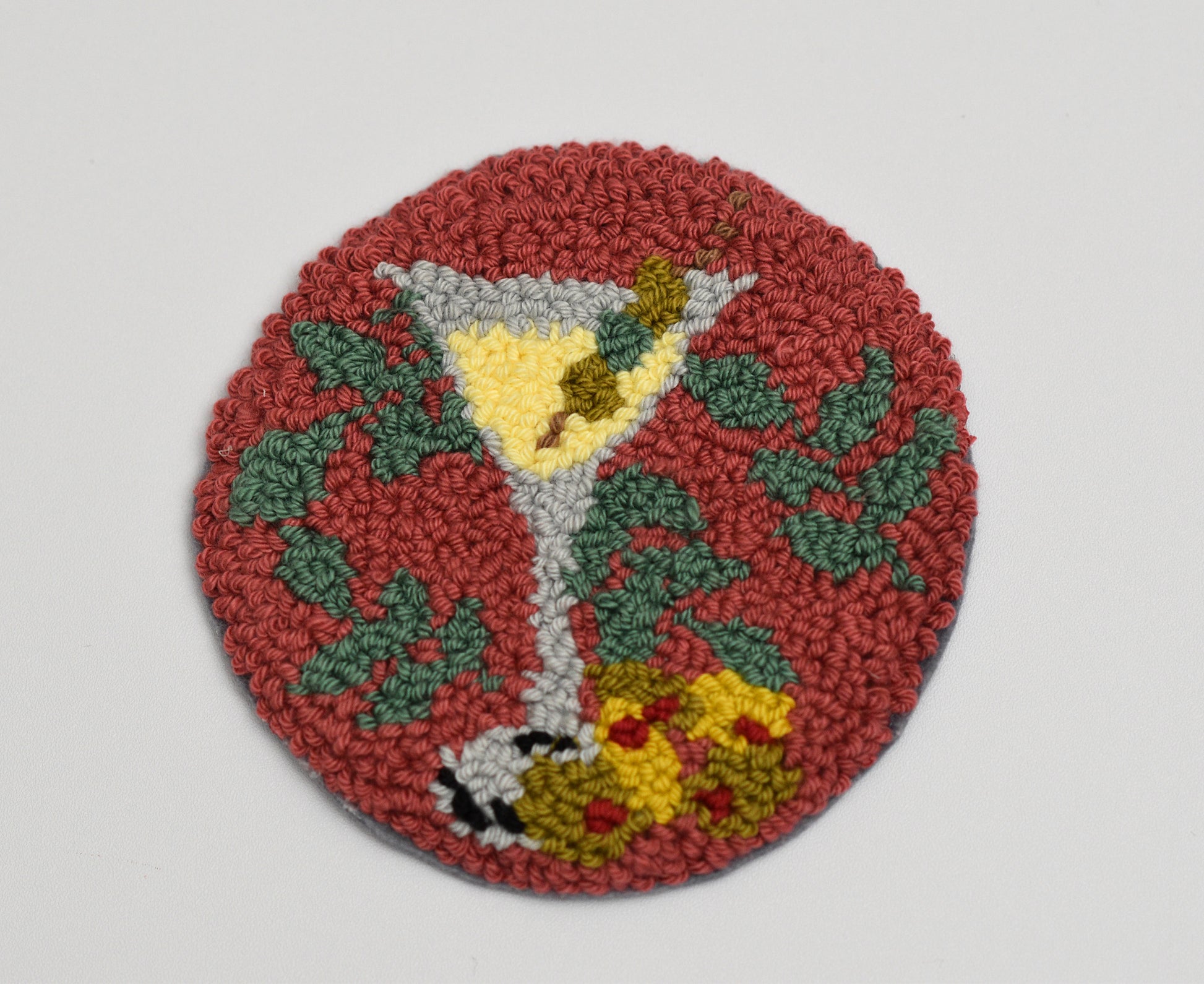 Round woven coaster with a martini glass design on a plain background