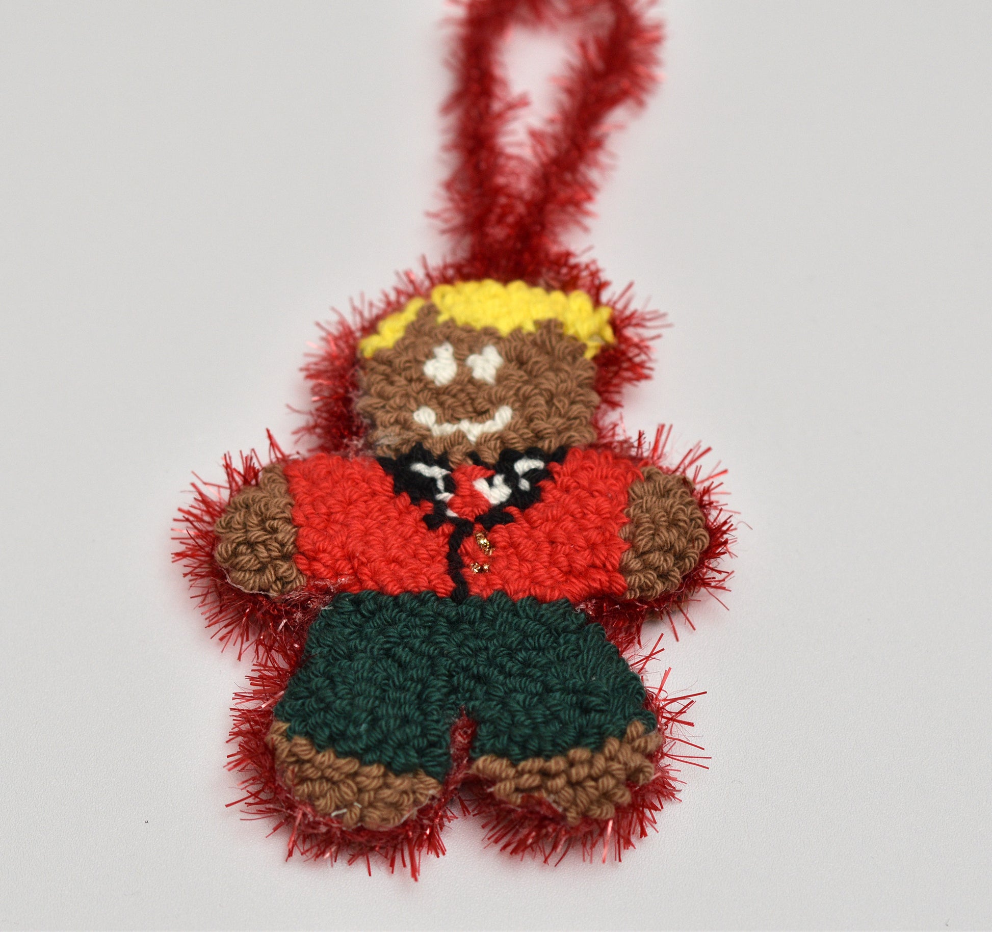 Punch needled gingerbread man with red jacket and green shorts on a white background