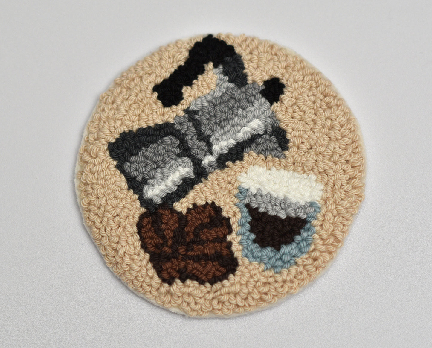 Round punch needled mug rug with a Espresso design on a plain background