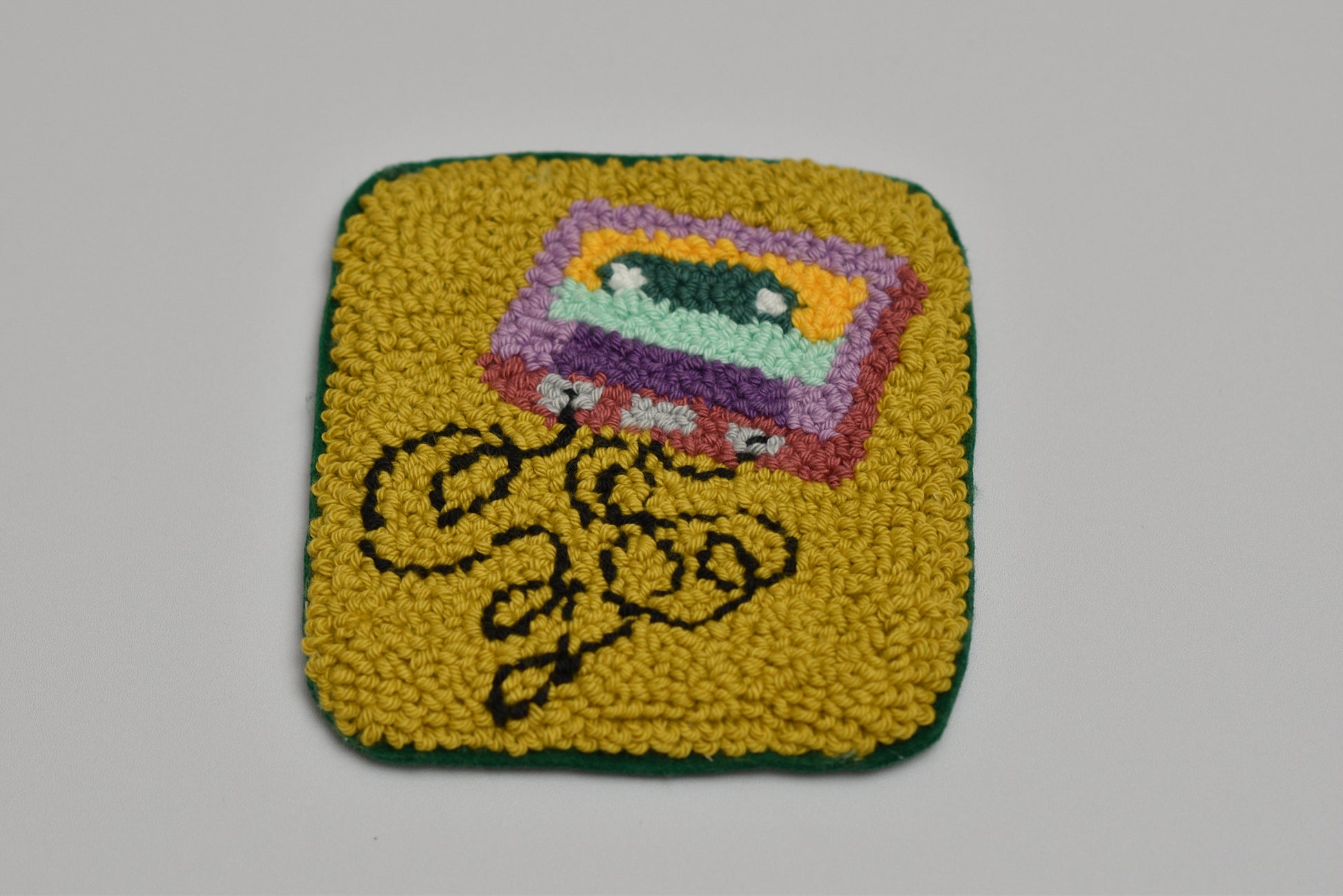 Square coaster with colorful cassette tape design on a gray background