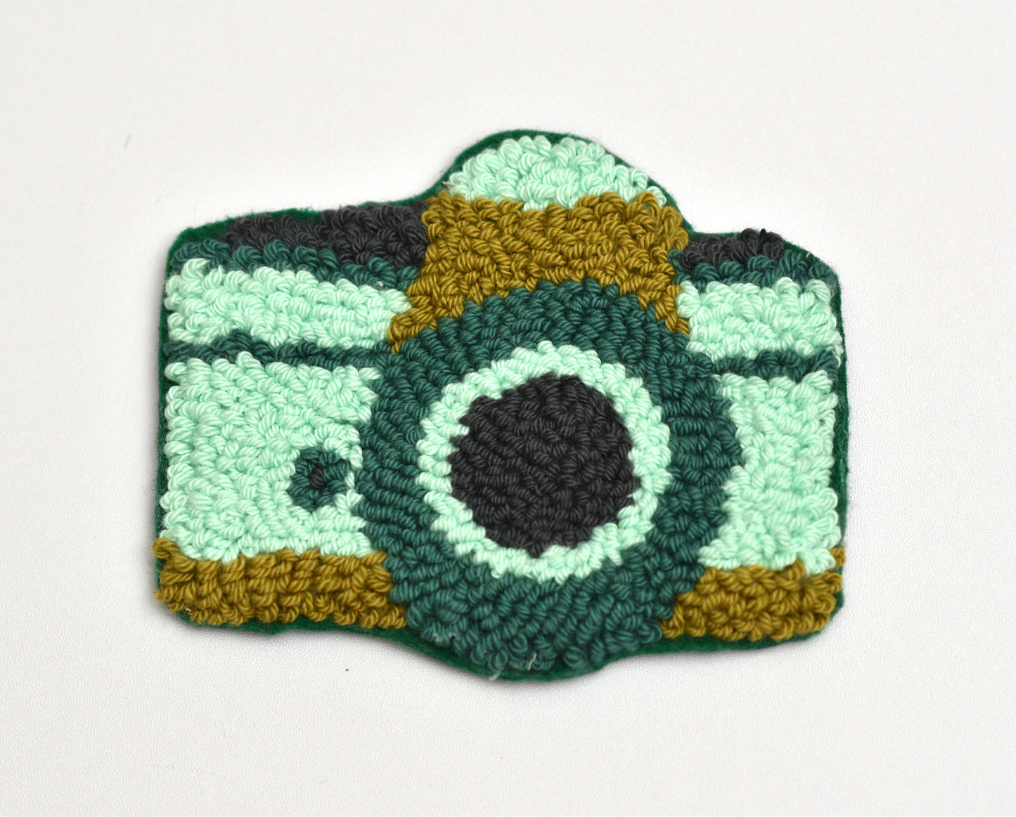 Punch needle camera-shaped coaster on a white background