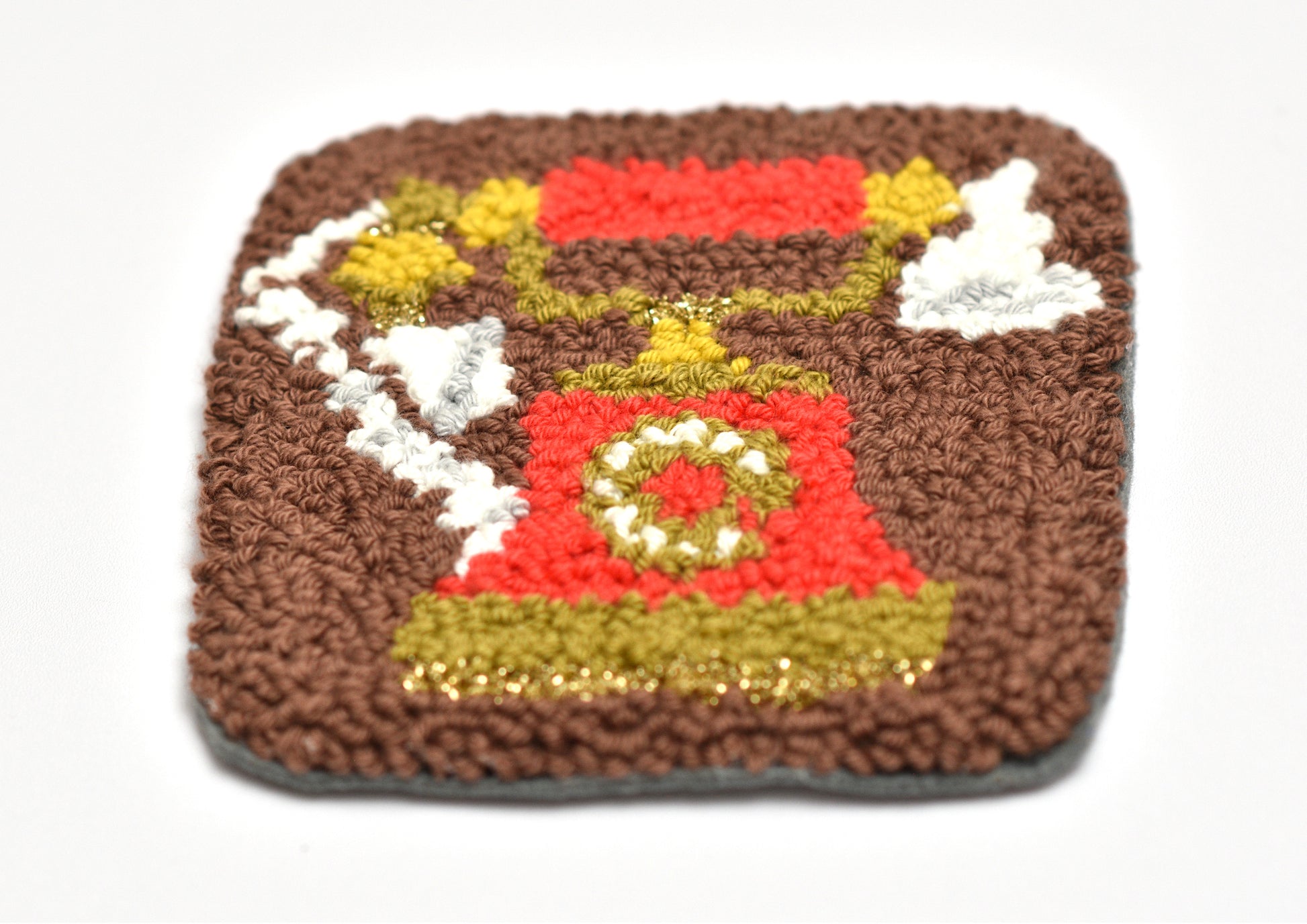 Square punch needle coaster with a red retro phone design on a white background